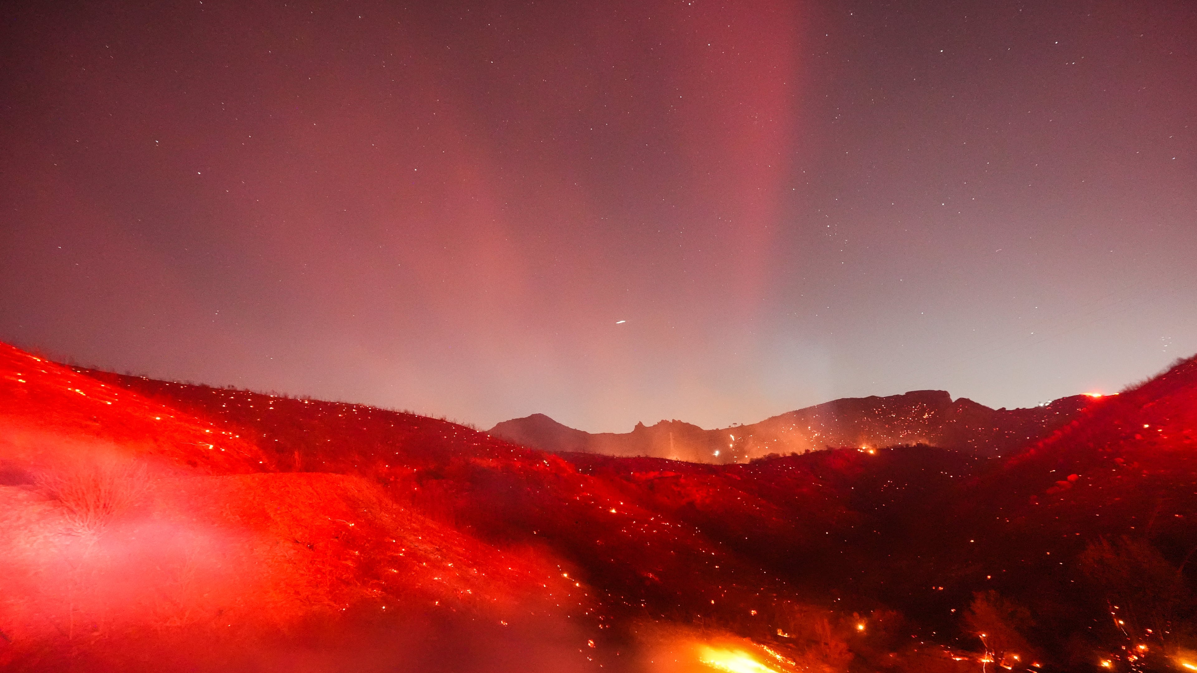 Hot spots glow across a hillside during the Bryson Fire in Malibu, Calif., Thursday, Oct. 15, 2026. (AP Photo/Jae C. Hong)