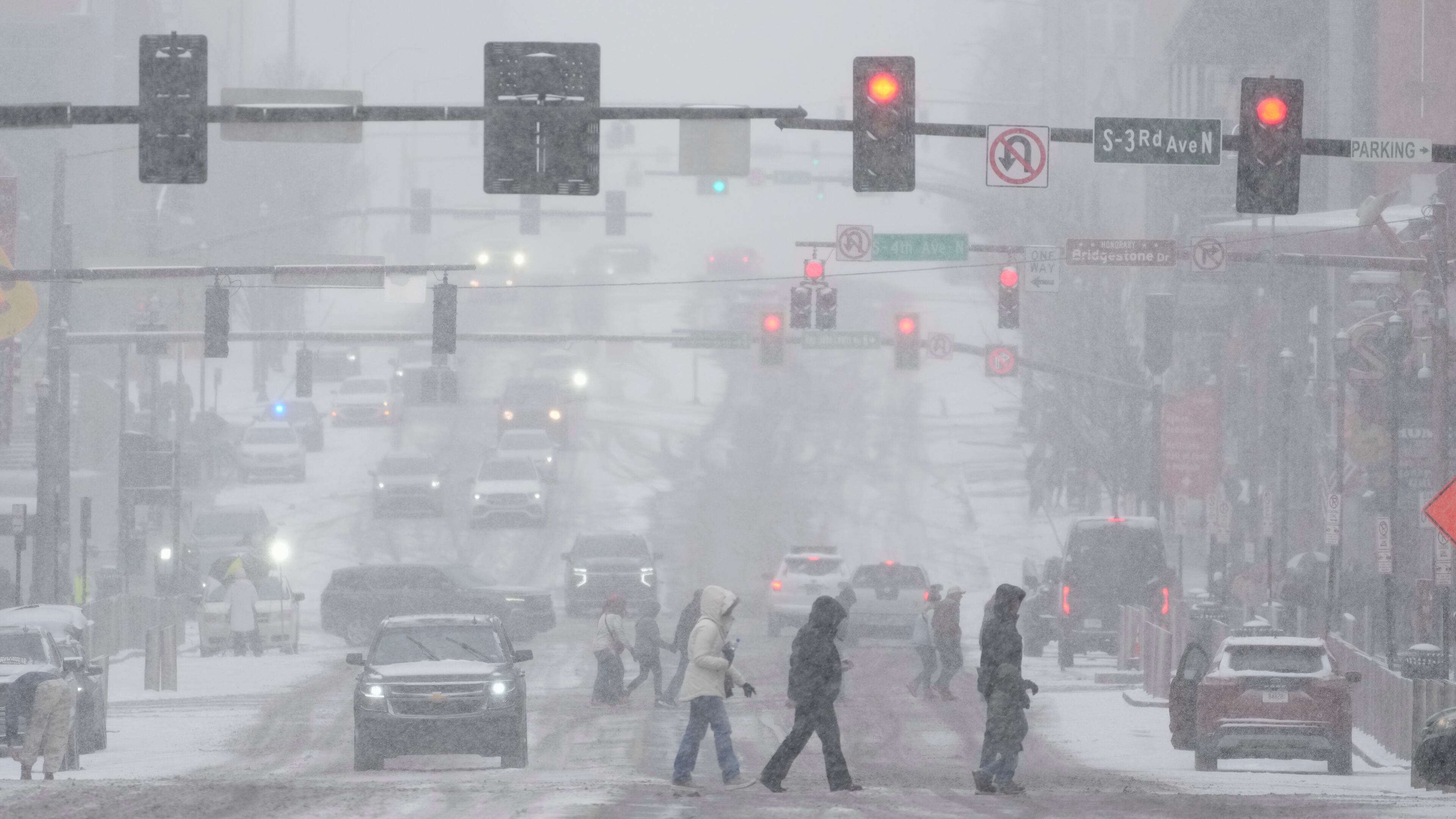 Pedestrians cross the street along Broadway during a winter storm Saturday, Jan. 24, 2026, in Nashville, Tenn. (AP Photo/George Walker IV)