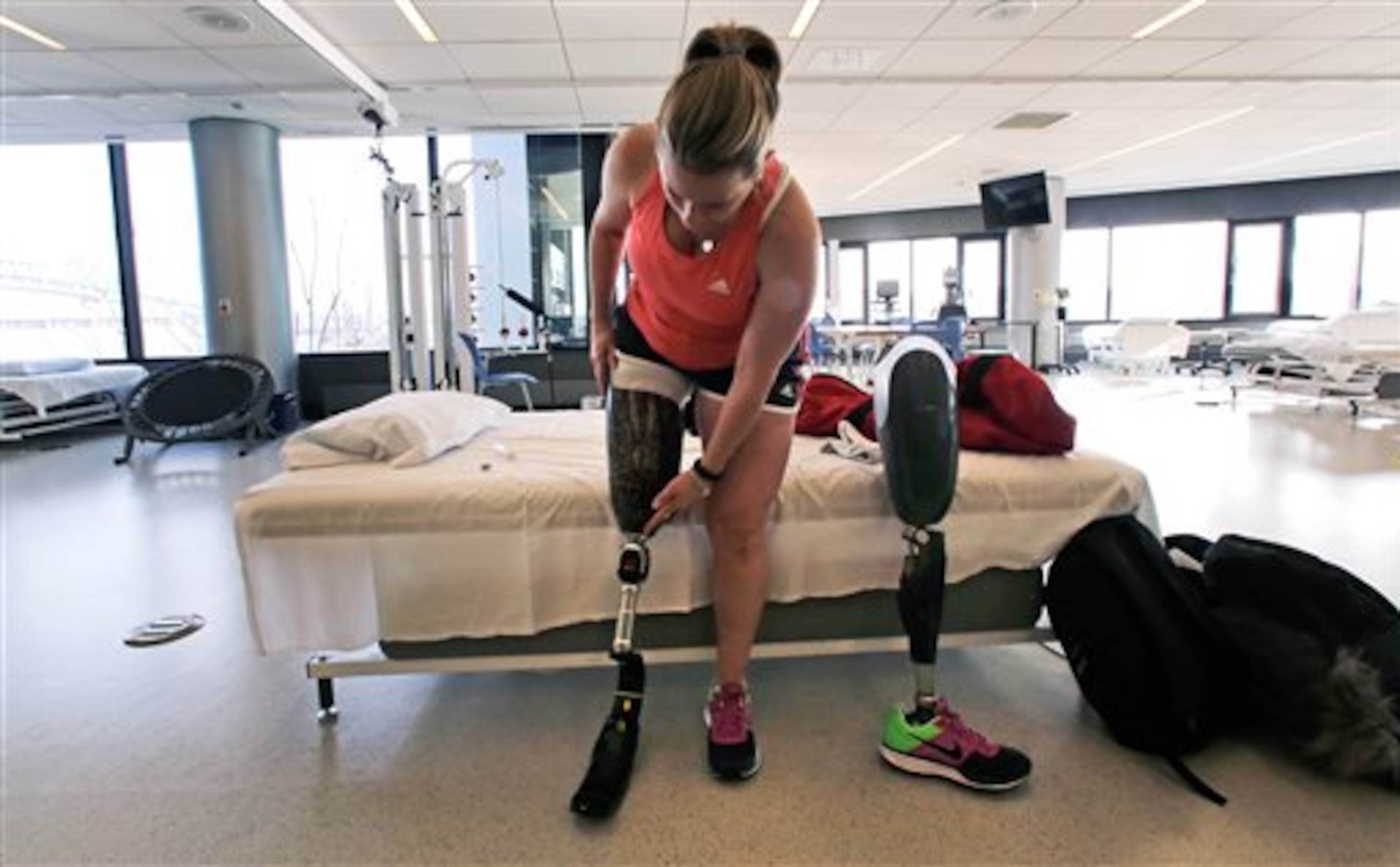 In this Tuesday, March 11, 2014 photo, Boston Marathon bombing survivor Roseann Sdoia adjusts her running blade as she switches her prosthetic legs during a therapy session at the Spaulding Rehabilitation Hospital in Boston. Sdoia, a runner who did not take part in the last year's Boston Marathon, was with friends in a crowd of fans near the finish line when one of two bombs went off nearby. (AP Photo/Charles Krupa)