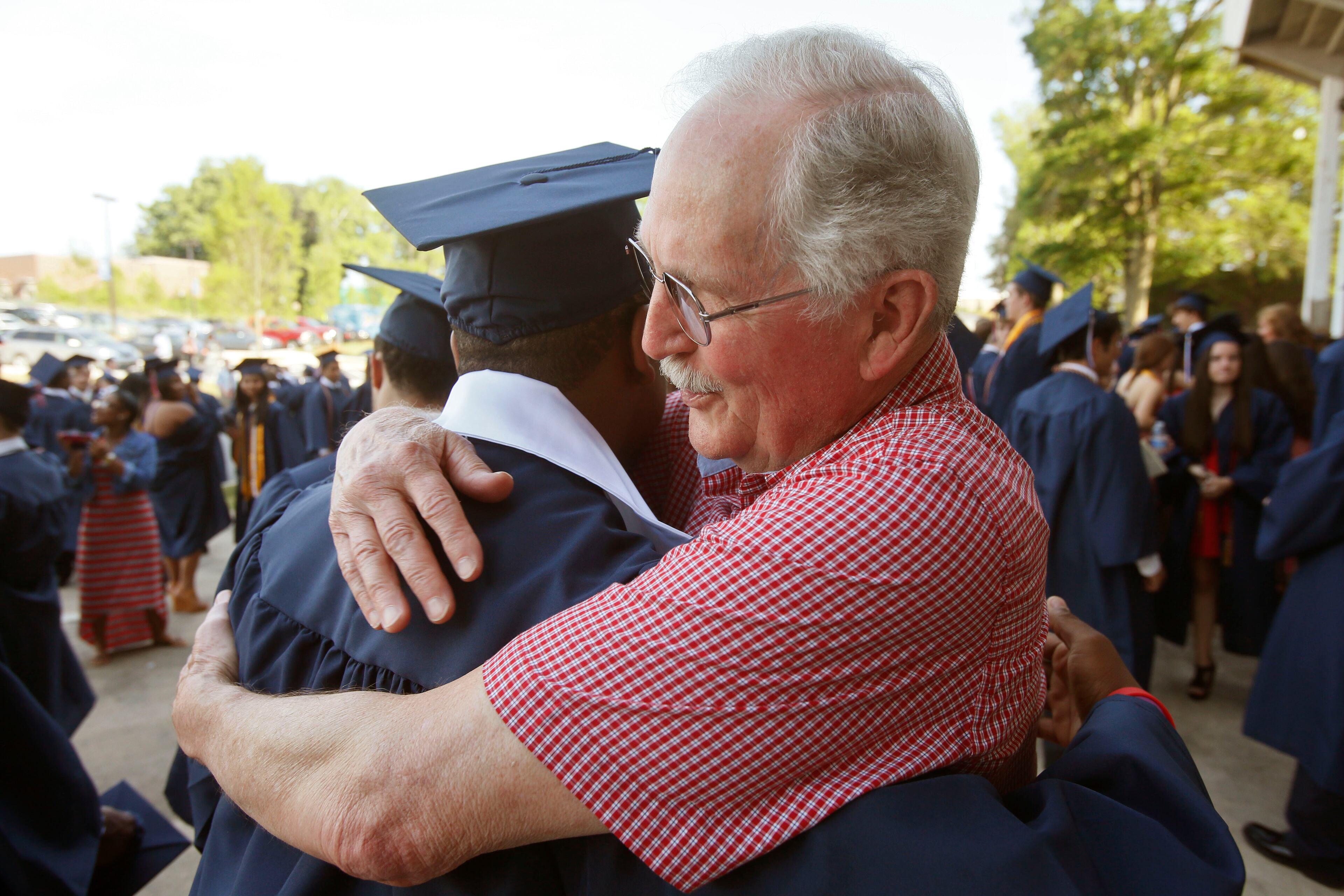 Art Collins (right) greets and gives Ashton Jordan a hug as they meet before Dunwoody High School graduation ceremonies at North Dekalb Stadium in Chamblee. BOB ANDRES / BANDRES@AJC.COM