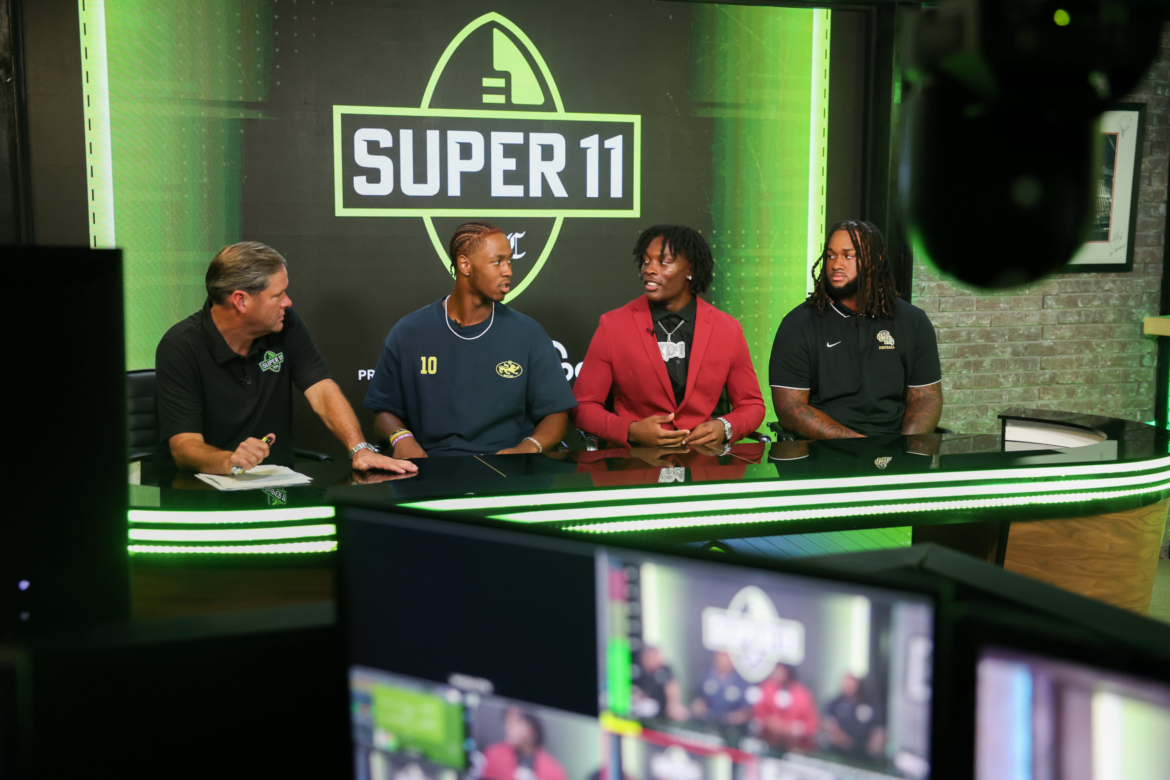 (L-R) DawgNation’s Brandon Adams interviews Stephenson’s Kwame “KJ” Green Jr., Hampton’s Kamarui Dorsey and Hughes’ Kelsey Adams Jr. during the taping of the Super 11 reveal show at Score ATL in Roswell on Aug. 3, 2026. (Arvin Temkar/AJC)