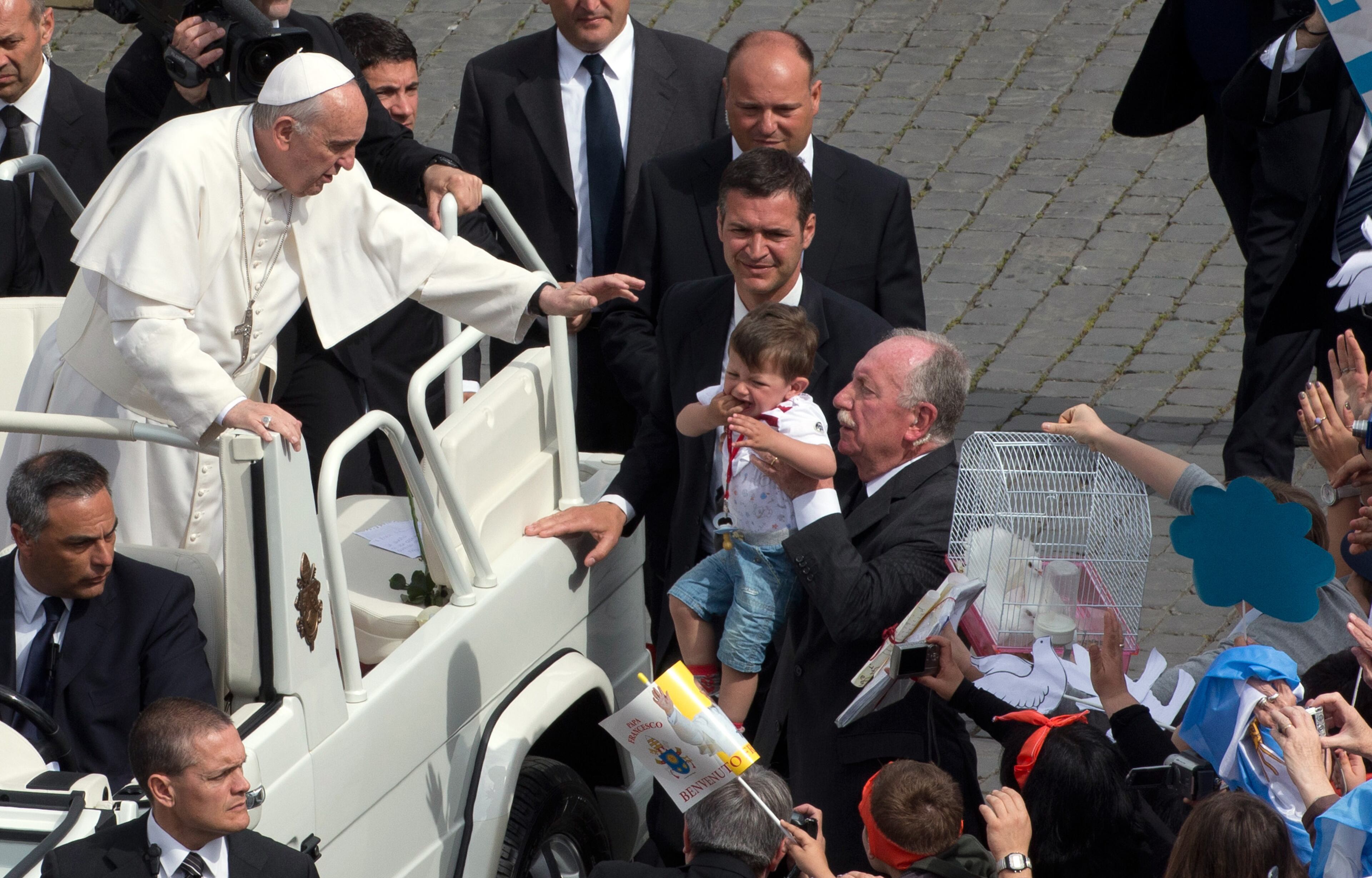 Faithful offer Pope Francis a cage containing two doves, right, during his weekly general audience in St. Peter Square at the Vatican, Wednesday, May 15, 2013. As Francis toured the square in his open-topped popemobile at his Wednesday audience with the public, someone at the edge of the crowd thrust a white bird cage at him. Looking puzzled, his security detail took the cage, containing a pair of white doves, and handed it to Francis. Without hesitation, the pope opened the cage door, thrust a hand inside and extracted one dove, and with a flick of his hand, sent the bird flying over the square. (AP Photo/Alessandra Tarantino)