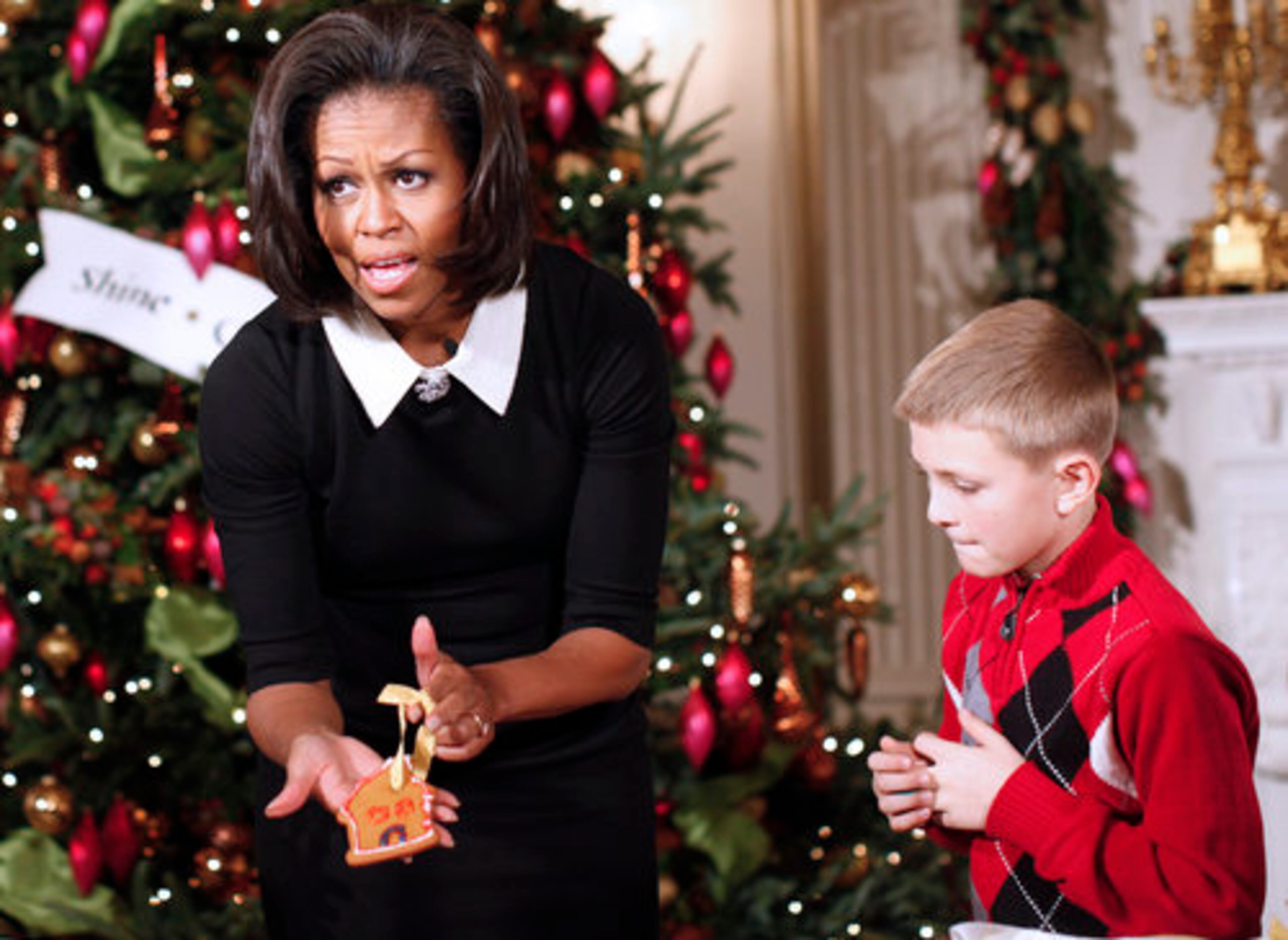 First lady Michelle Obama shows a gingerbread cookie she decorated with children from military families, in the State Dining Room of the White House.