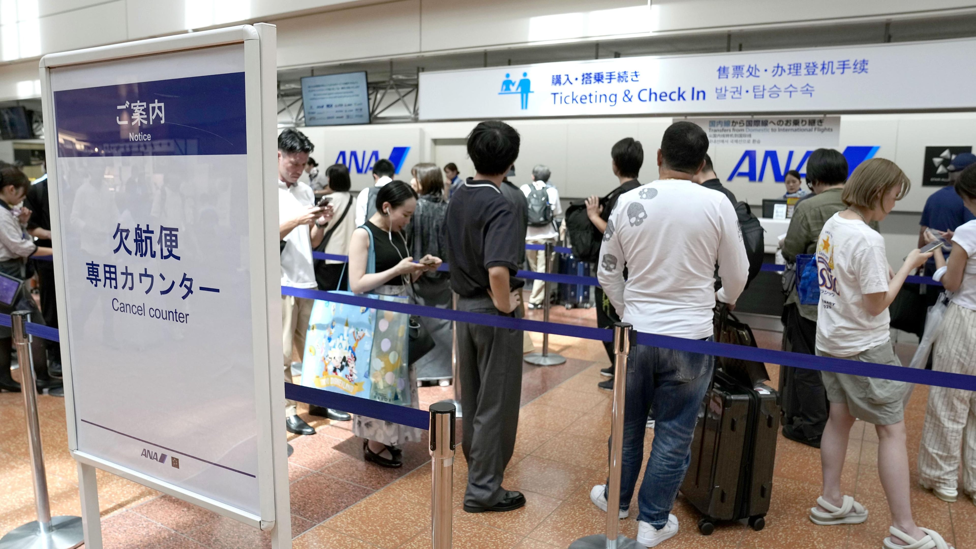 Passengers line up in front of an All Nippon Airways counter at Haneda airport in Tokyo following flight cancellations due to Tropical Storm Chan-hom Tuesday, Aug. 11, 2026. (Katsuya Miyagawa/Kyodo News via AP)