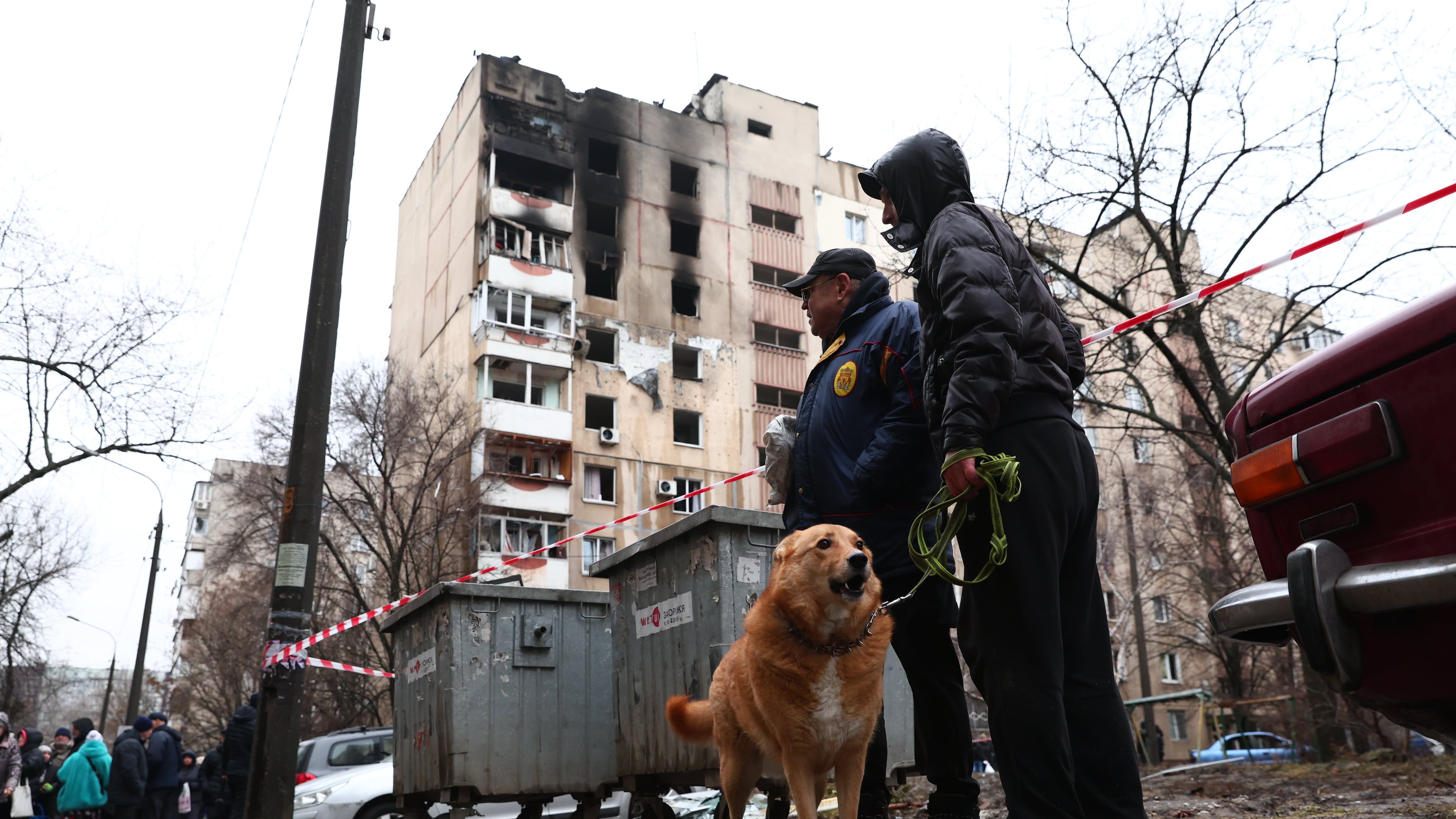 Local residents walk a dog near a damaged apartment building hit by Russian drone in Zaporizhzhia, Ukraine, Thursday, Feb. 26, 2026. (AP Photo/Kateryna Klochko)