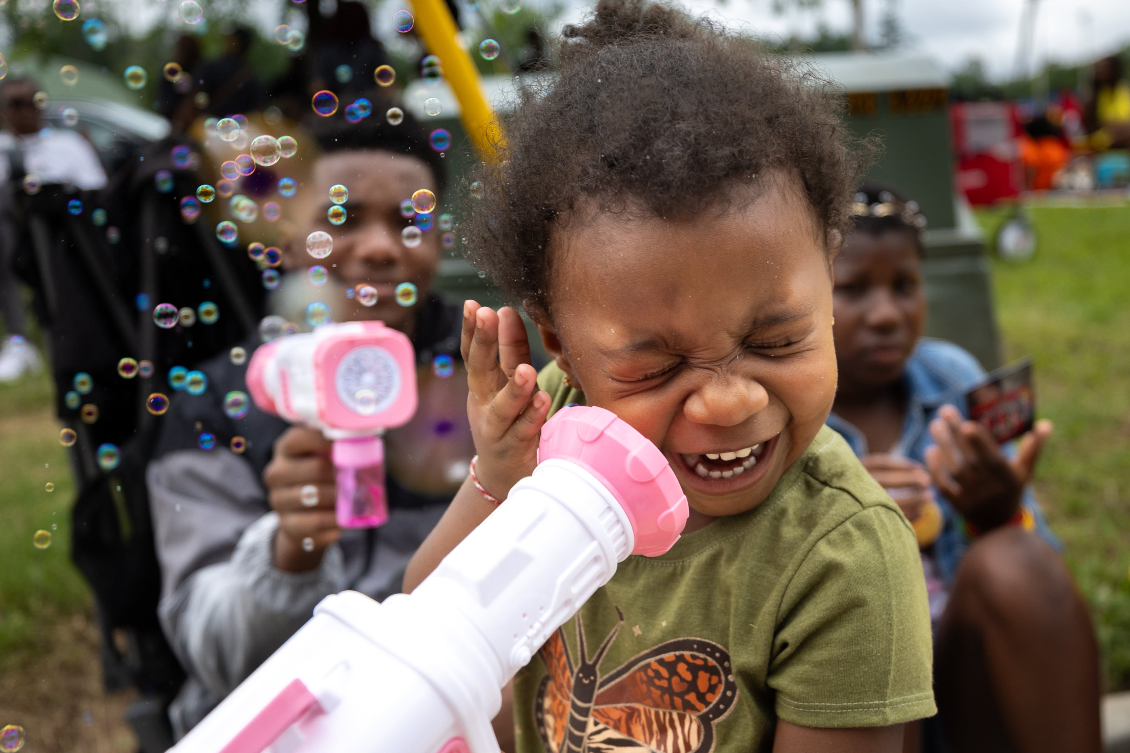 Emersen Willis, 2, laughs as her brother Tristan sprays her with bubbles during the Juneteenth parade in College Park on Thursday, June 19, 2025. (Arvin Temkar / AJC)