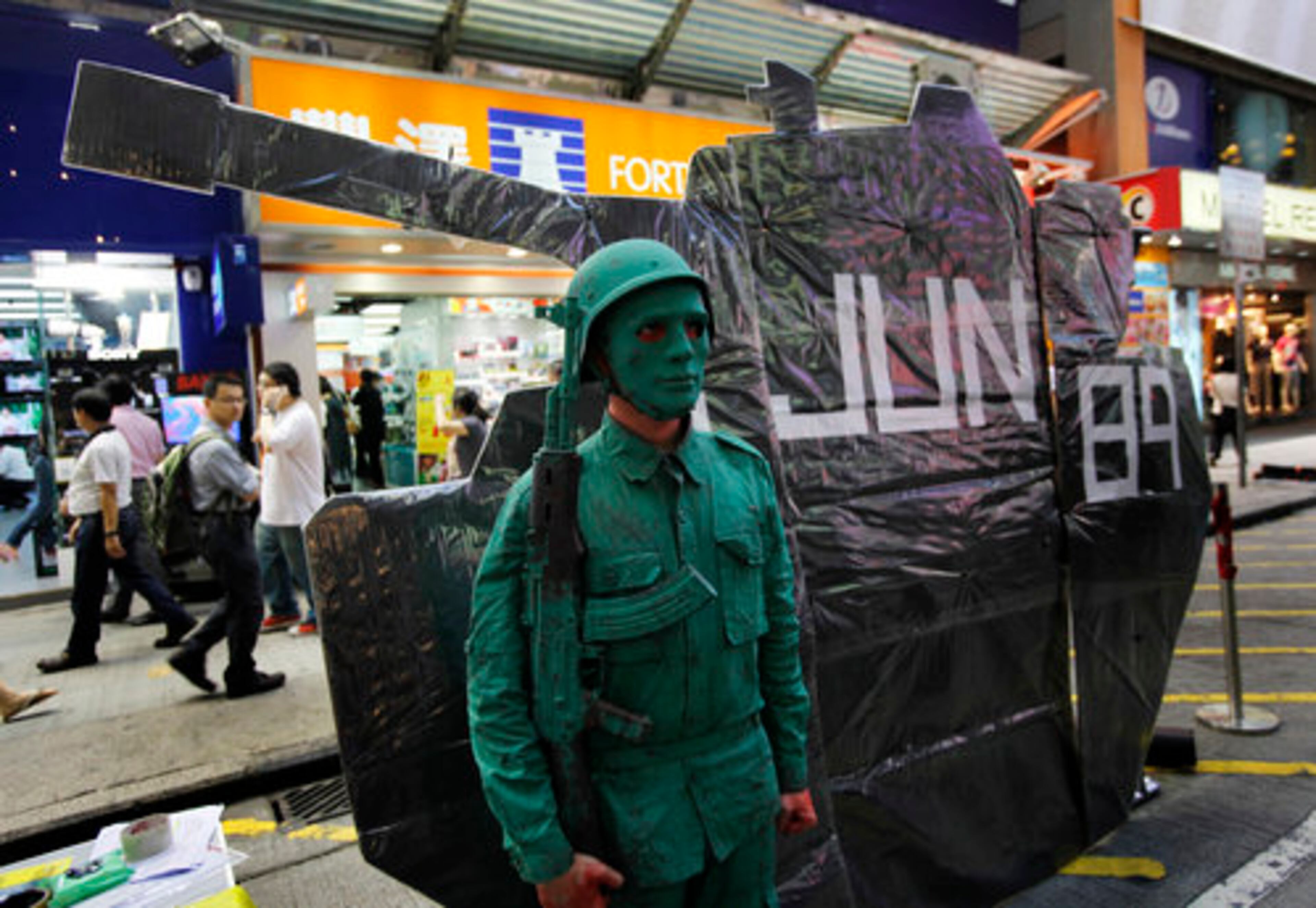 A mime artist dressed as a Chinese PLA soldier stands next to a cutout of a tank during a street drama in a downtown street in Hong Kong Wednesday.