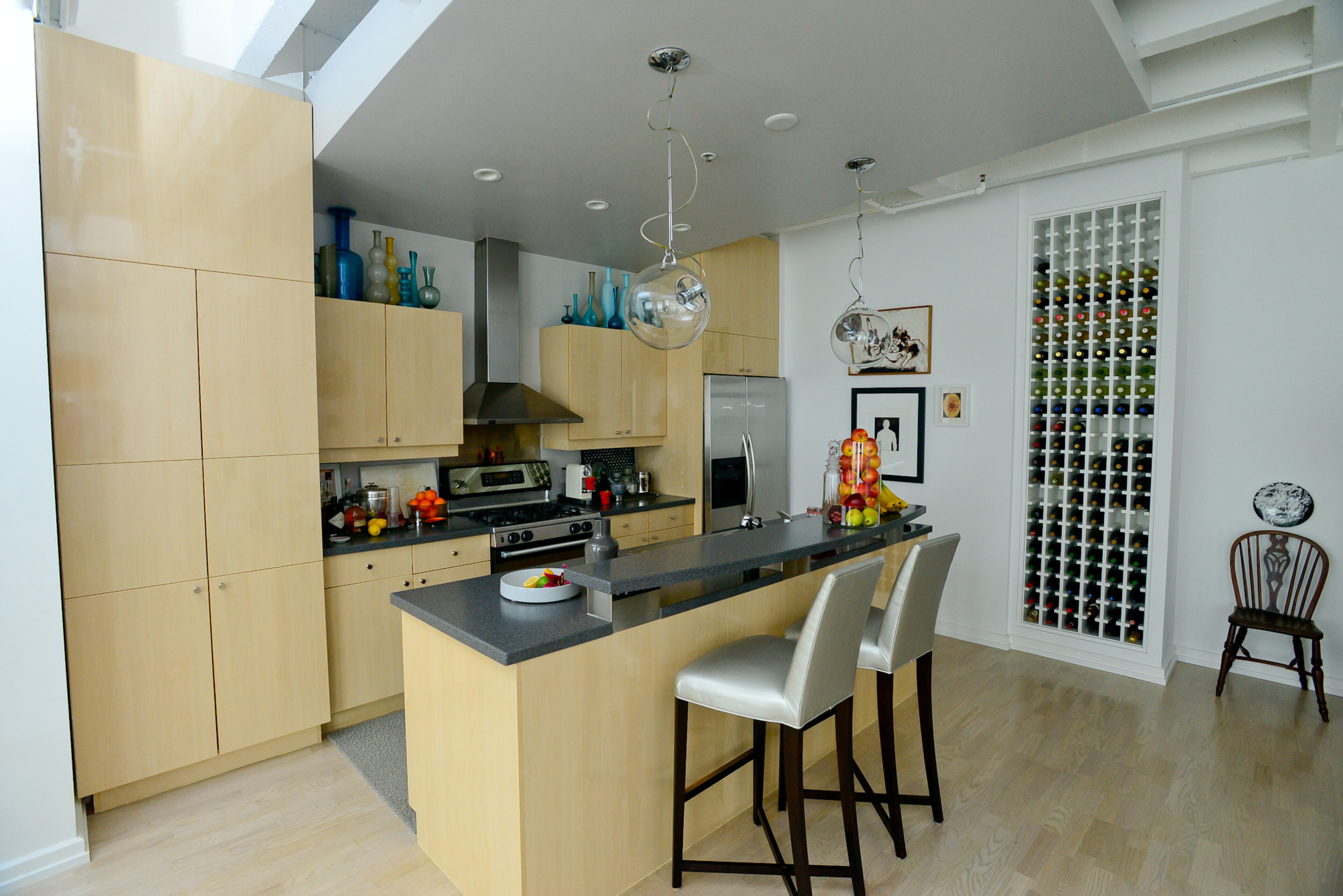 Cabinets from SieMatic reach to the ceiling, painted Benjamin Moore's Harbor Gray, in the Midtown Atlanta condo. The counter stools are covered in Pollack fabric.