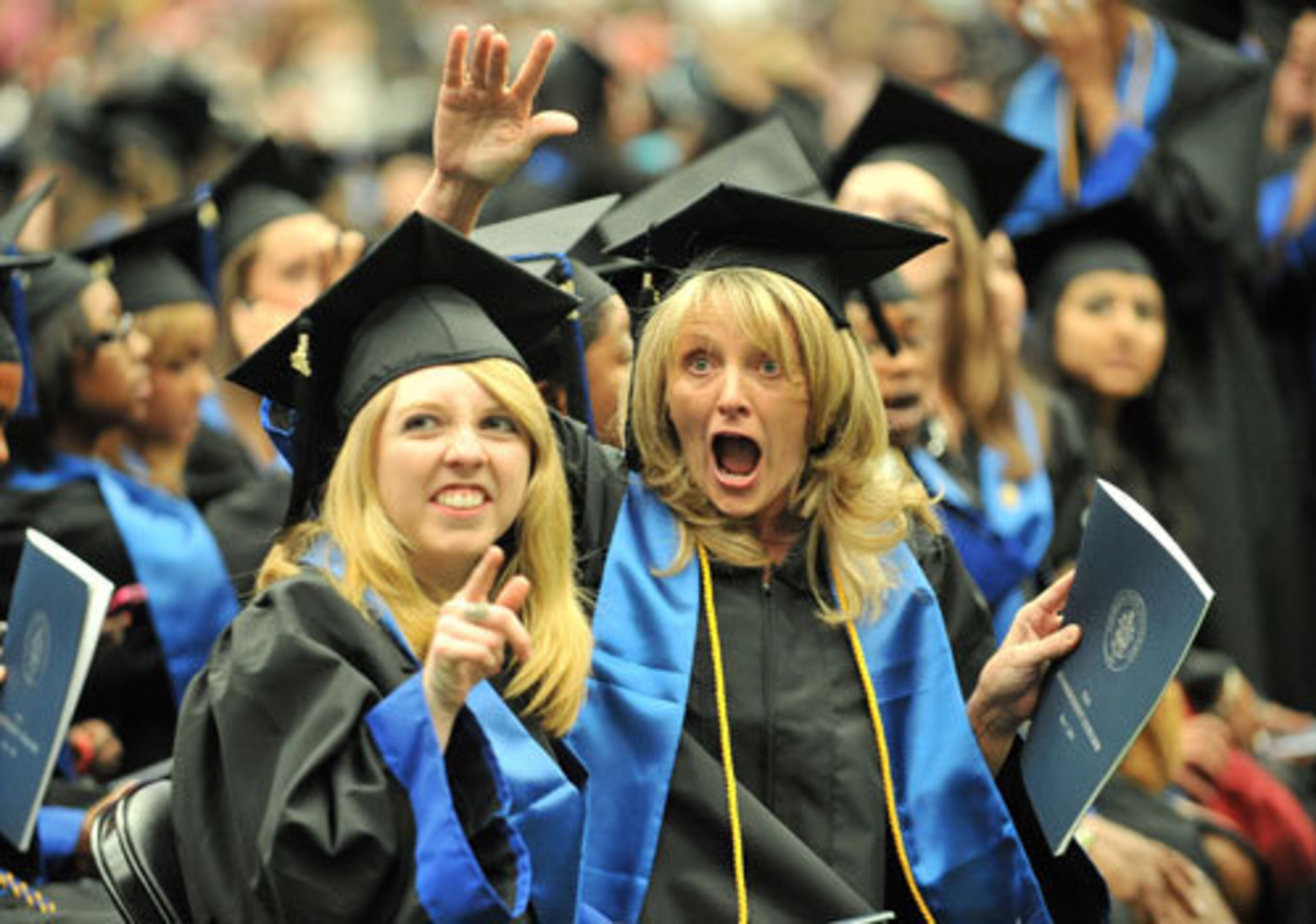 Jacquelyn Whalen, left, and Laura Zimmerman, both Social Work majors, wave during the graduation ceremony.