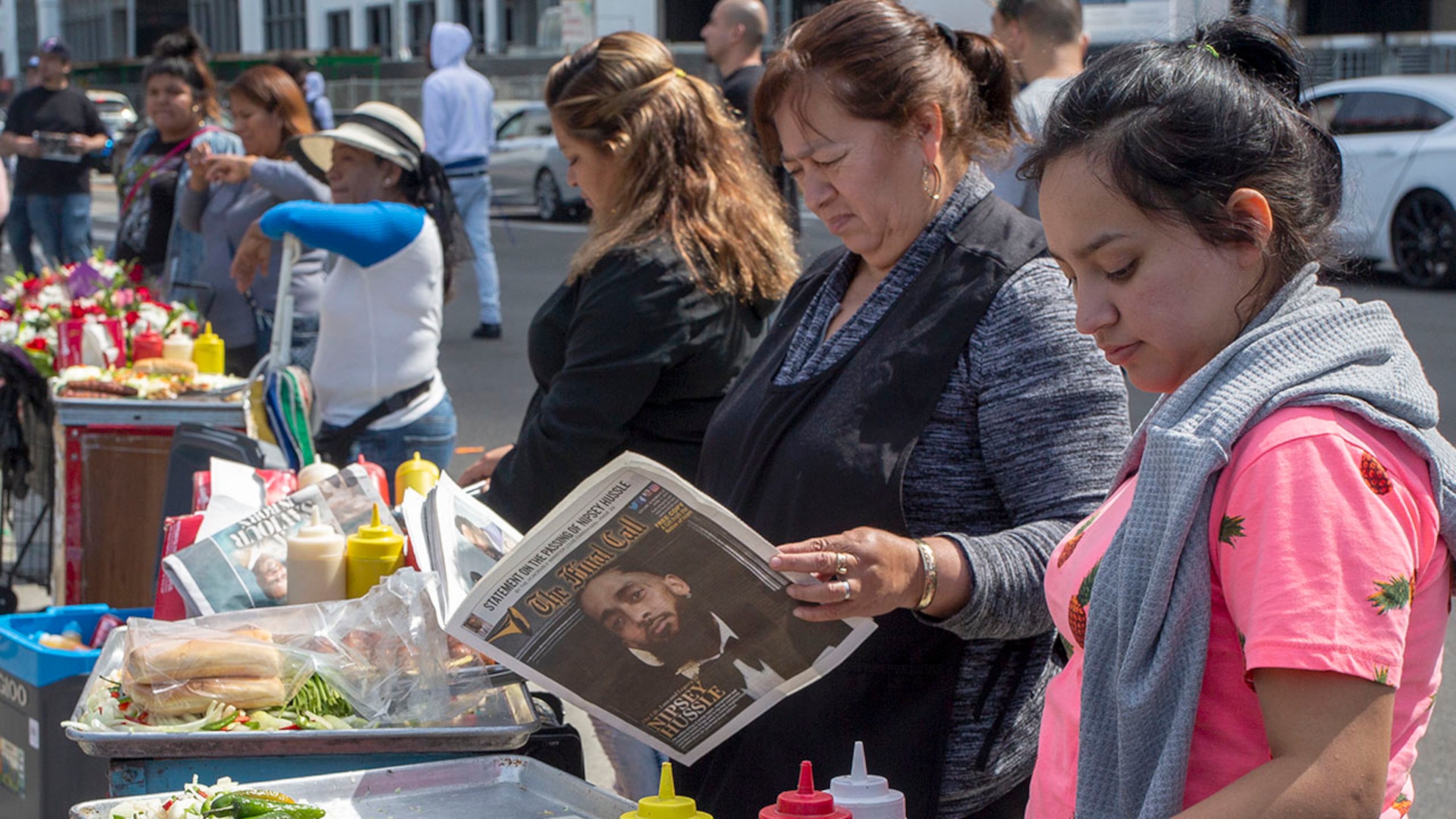 LOS ANGELES, CA - APRIL 11: A street vendor reads a Nation of Islam publication honoring slain rapper Nipsey Hussle outside a memorial celebration for him at the Staples Center arena on April 11, 2019 in Los Angeles, California. Nipsey Hussle was shot and killed in front of his store, The Marathon Clothing, on March 31, 2019 in Los Angeles. (Photo by David McNew/Getty Images)