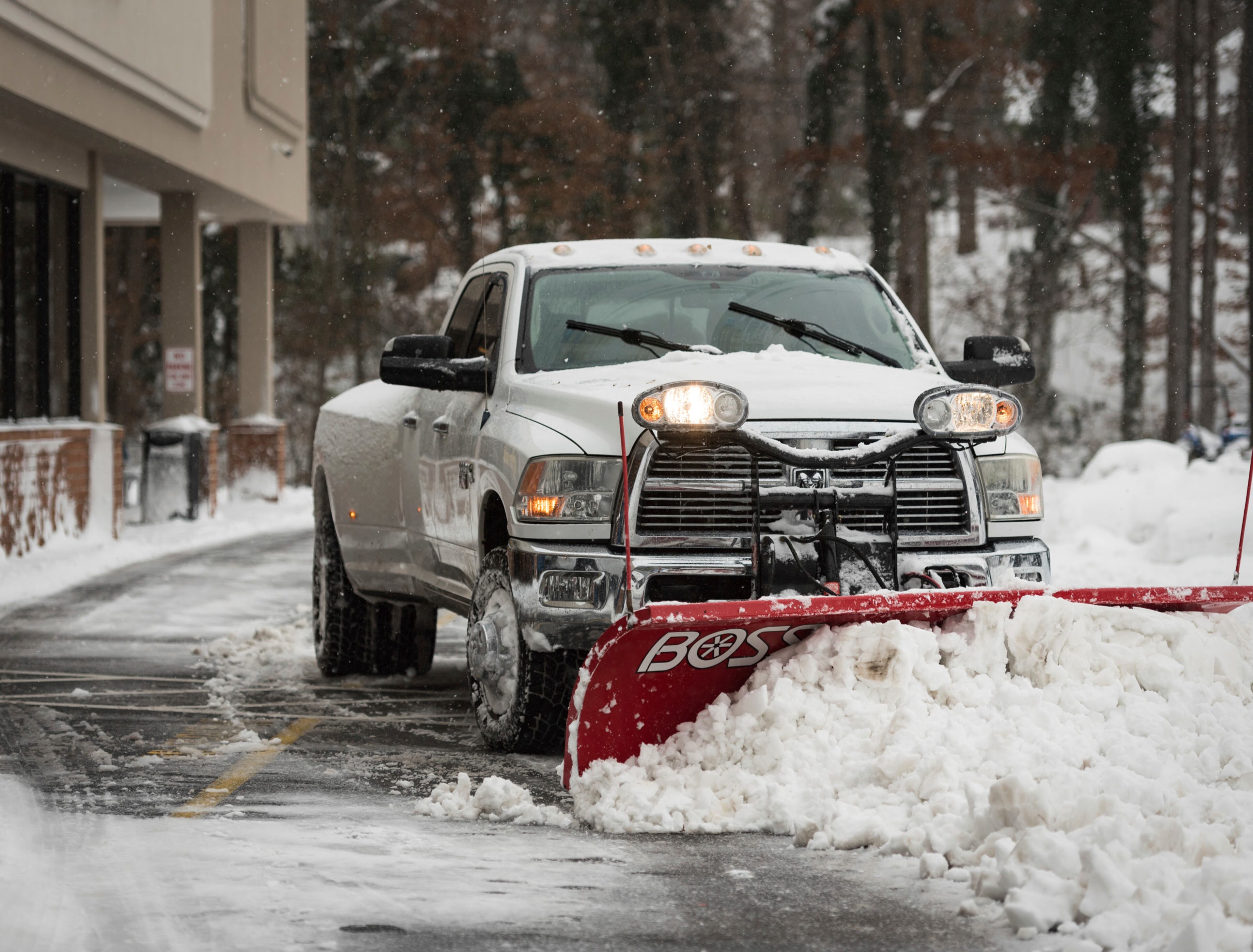 A truck plows through snow in the Food Lion parking lot Sunday, Dec. 9, 2018, on South Hawthorne Road in Winston-Salem, N.C. (Allison Lee Isley/The Winston-Salem Journal via AP)