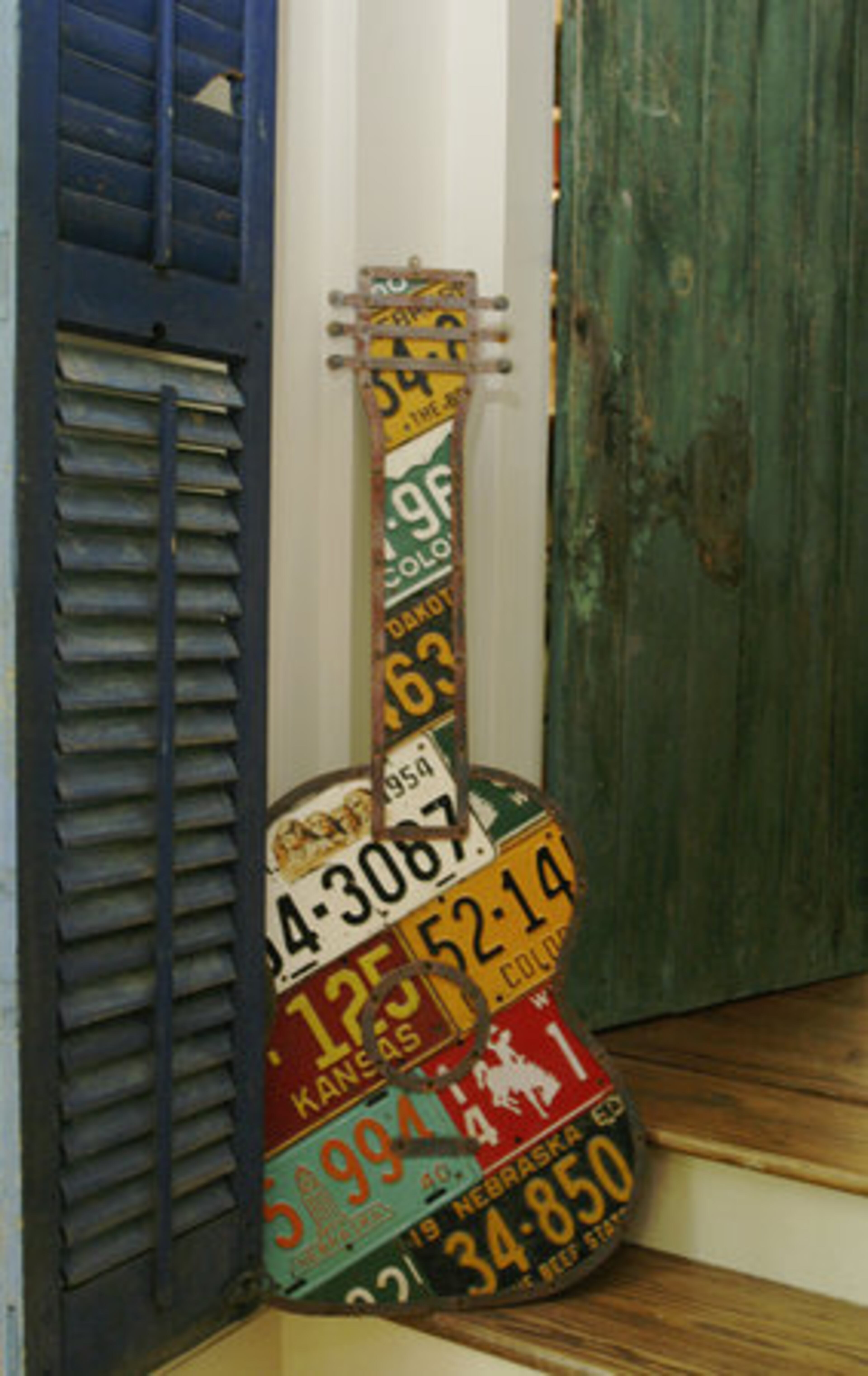 This guitar fabricated from vintage license plates rests by the entry to the library which has weathered doors sourced from St. Remy in the South of France.