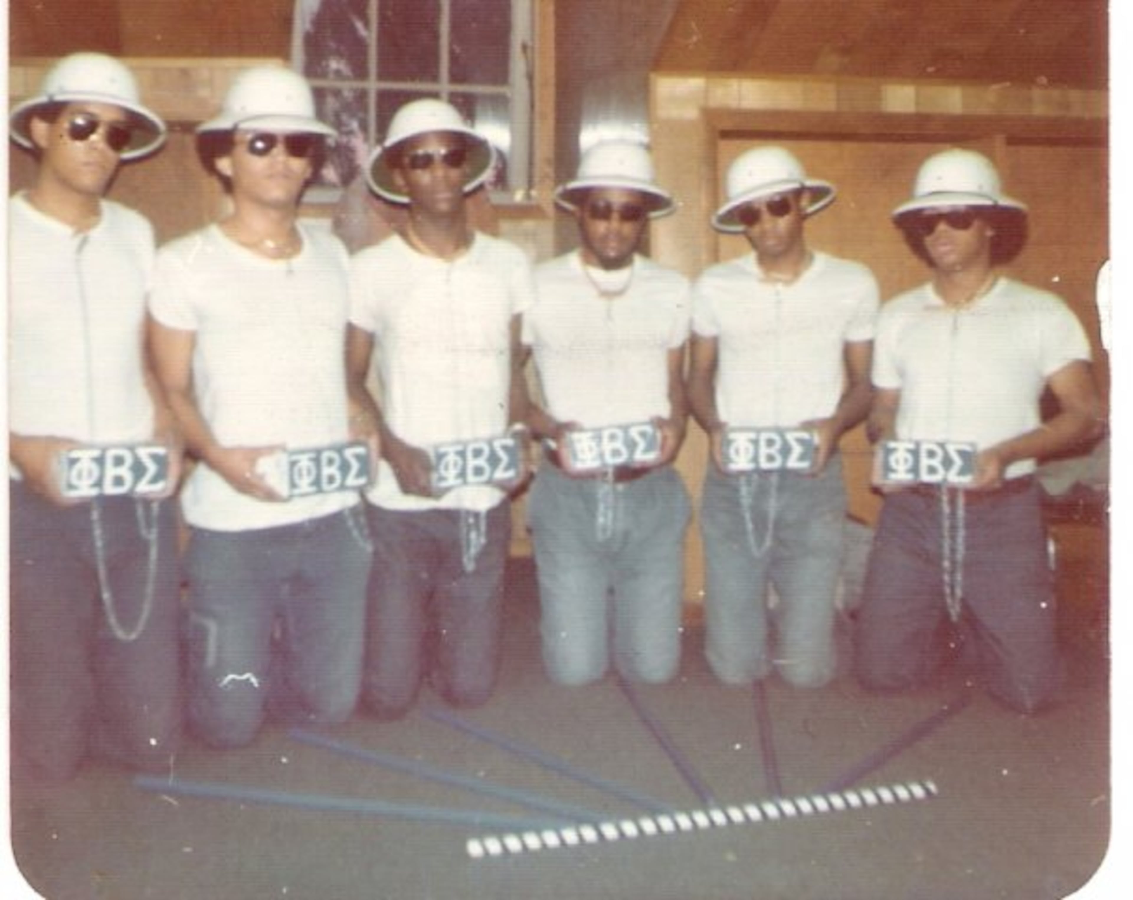 April 1974. Hell Week for the Beta Gamma Crescents at Hampton Institute. Dubbed "The Genesis Line," they wore white pith helmets and carried bricks. From left: David Washington, David Gibson, Wayne Dixon, Jerald Blake, Charles Johnson, John Fisher.