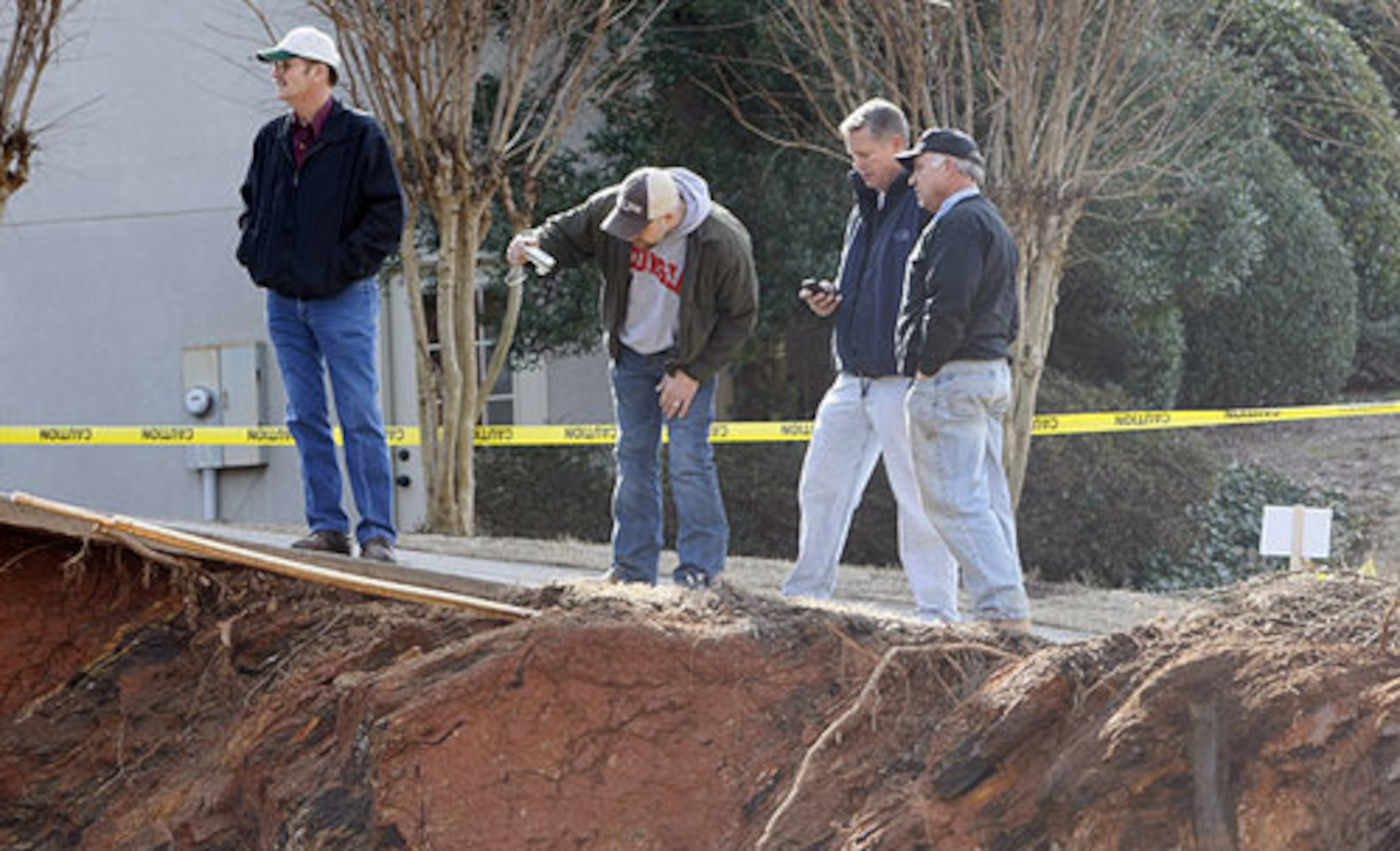Officials assess the situation. Crews began working Thursday morning to fill in a massive sinkhole that swallowed a large chunk of a front yard in Marietta. The sinkhole forced the homeowner to evacuate and swallowed three trees.