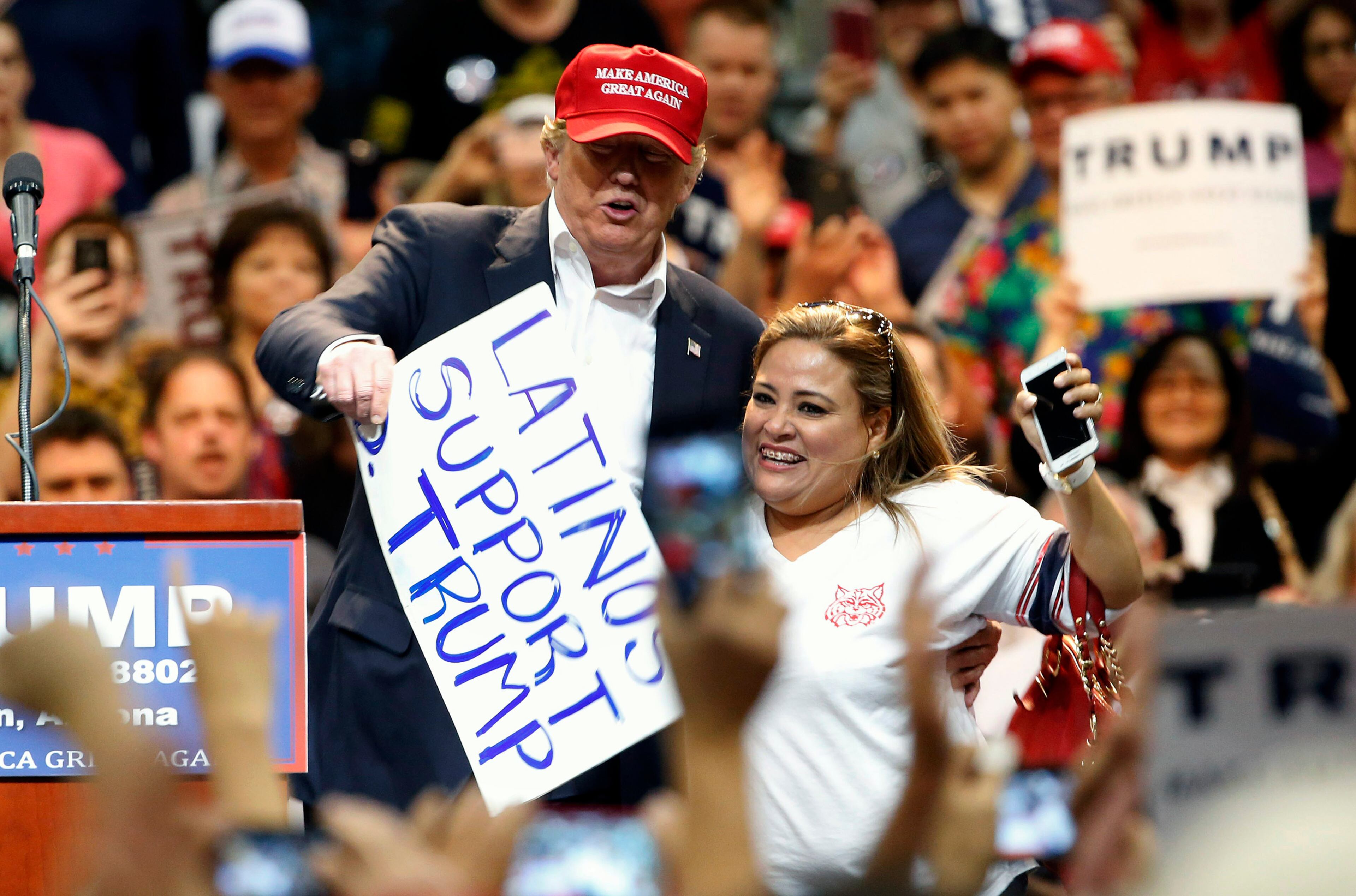 Republican presidential candidate Donald Trump, left, brings a supporter up on stage because he liked her sign as Trump speaks during a campaign rally Saturday, March 19, 2016, in Tucson, Ariz. (AP Photo/Ross D. Franklin)