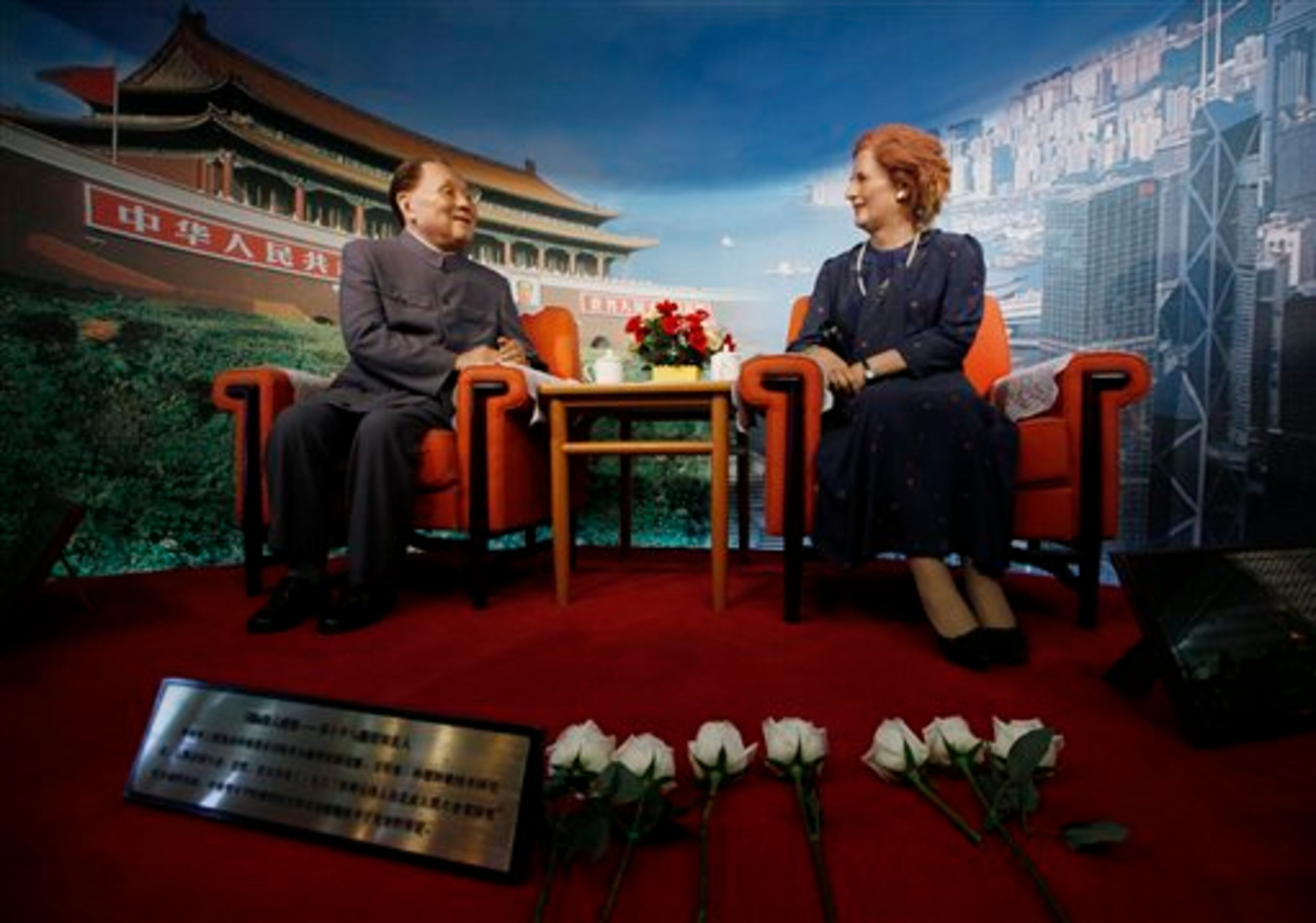 Flowers are laid by staff members in front of the wax statue of former British Prime Minister Margaret Thatcher, right, following her death in an exhibition center in Shenzhen, China Tuesday, April 9, 2013. Margaret Thatcher, the combative "Iron Lady" who infuriated European allies, found a fellow believer in Ronald Reagan and transformed her country by a ruthless dedication to free markets in 11 bruising years as prime minister, died Monday, April 8, 2013. She was 87 years old. The wax statue at left is of former Chinese leader Deng Xiaoping. (AP Photo/Kin Cheung)