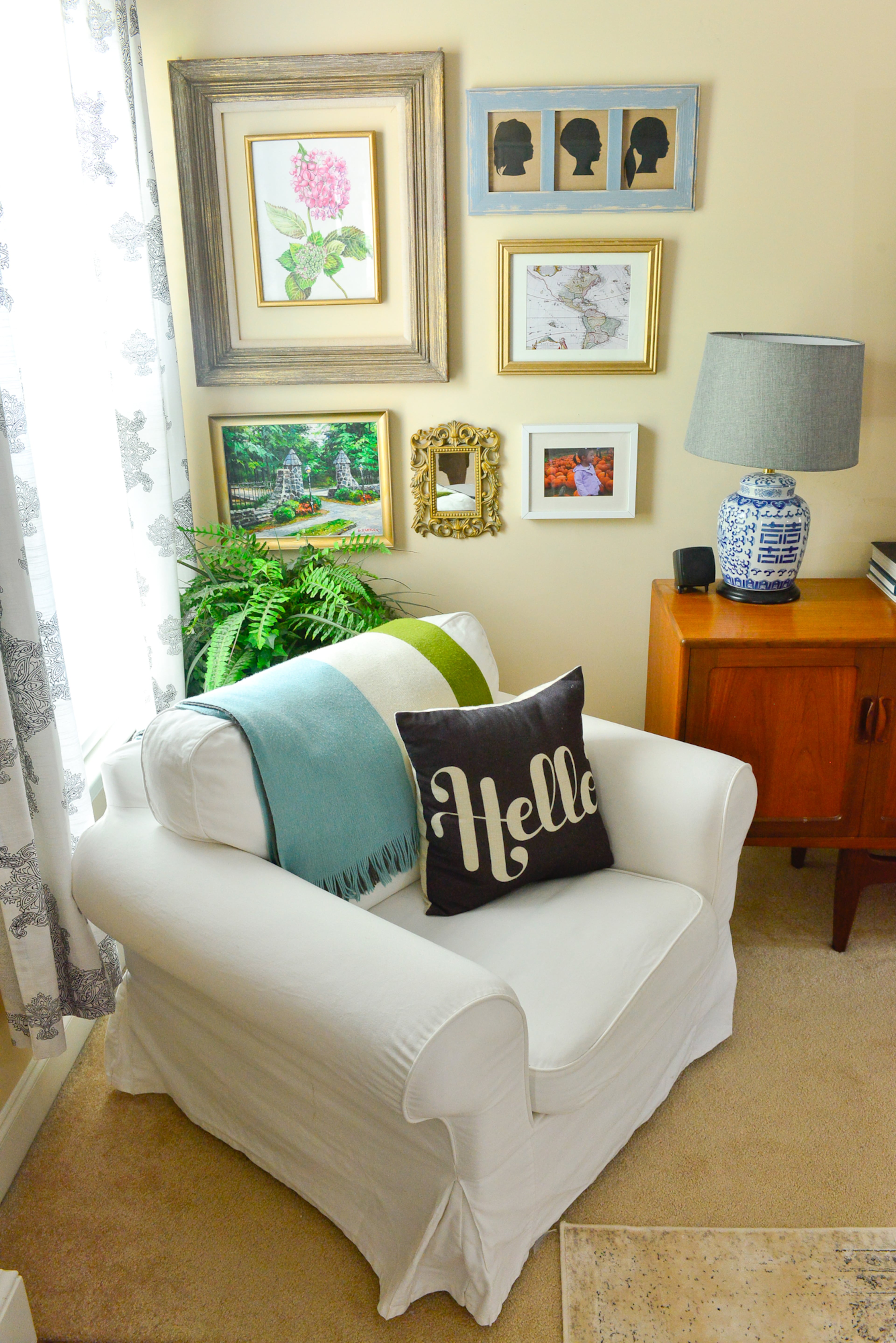 Living room: A gallery wall with mirrors and botanical art adds pops of color to the living room. The white Ikea chair has a slipcover that can be washed.