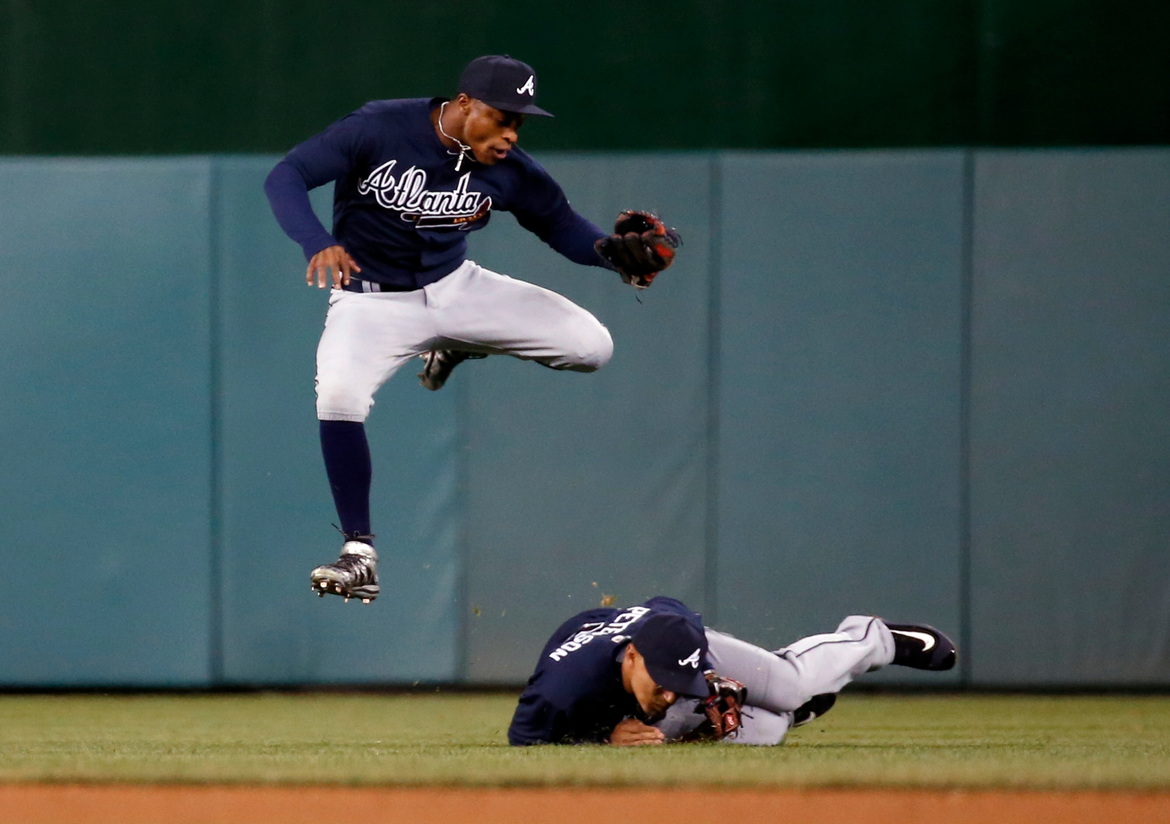 Atlanta Braves center fielder Mallex Smith jumps over second baseman Jace Peterson (8) after Smith caught a fly ball hit by Washington Nationals' Wilson Ramos during the fourth inning of a baseball game at Nationals Park, Wednesday, April 13, 2016, in Washington. (AP Photo/Alex Brandon)