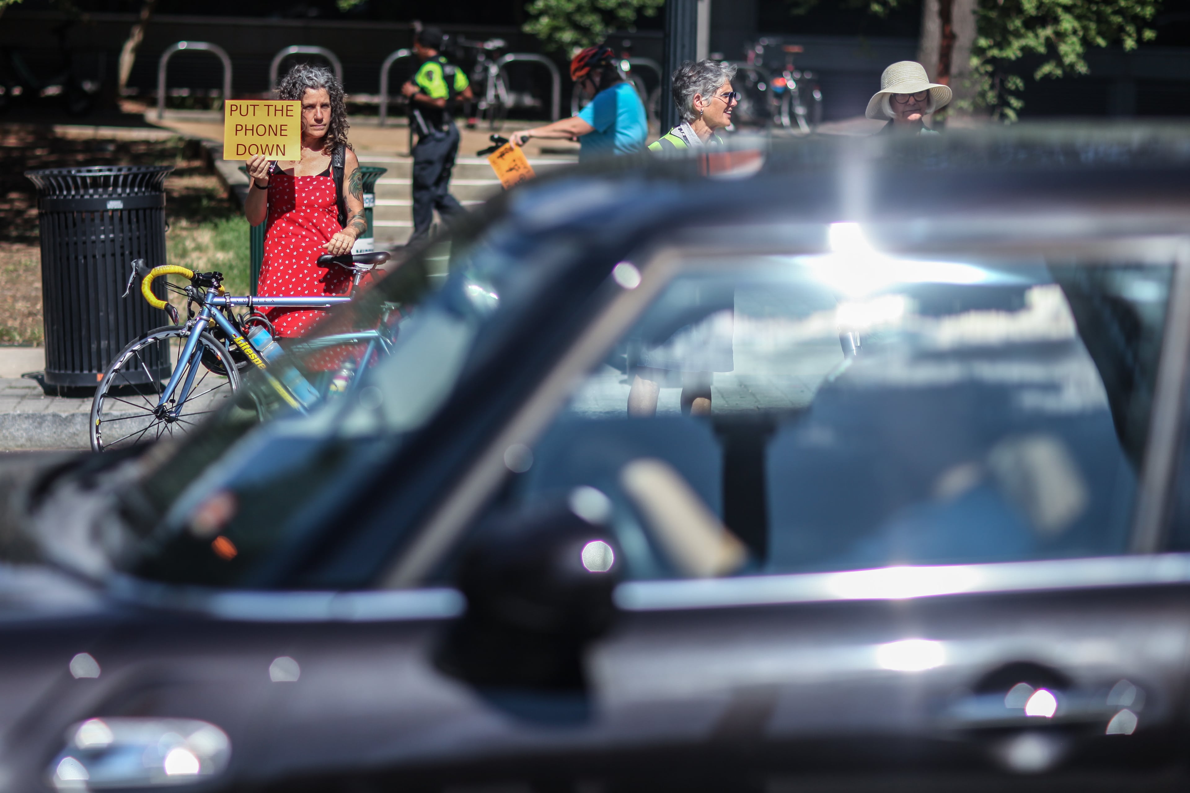 Kat Jones, left, holds a sign during a rally on West Peachtree Street near 15th Street where William Alexander was hit and killed by a bus while riding on a scooter, Wednesday, July 24, 2019, in Atlanta. Organizers joined together as a "human protected sidewalk, bike and scooter lane" demanding the city prioritize protected bike and scooter lanes. BRANDEN CAMP/SPECIAL