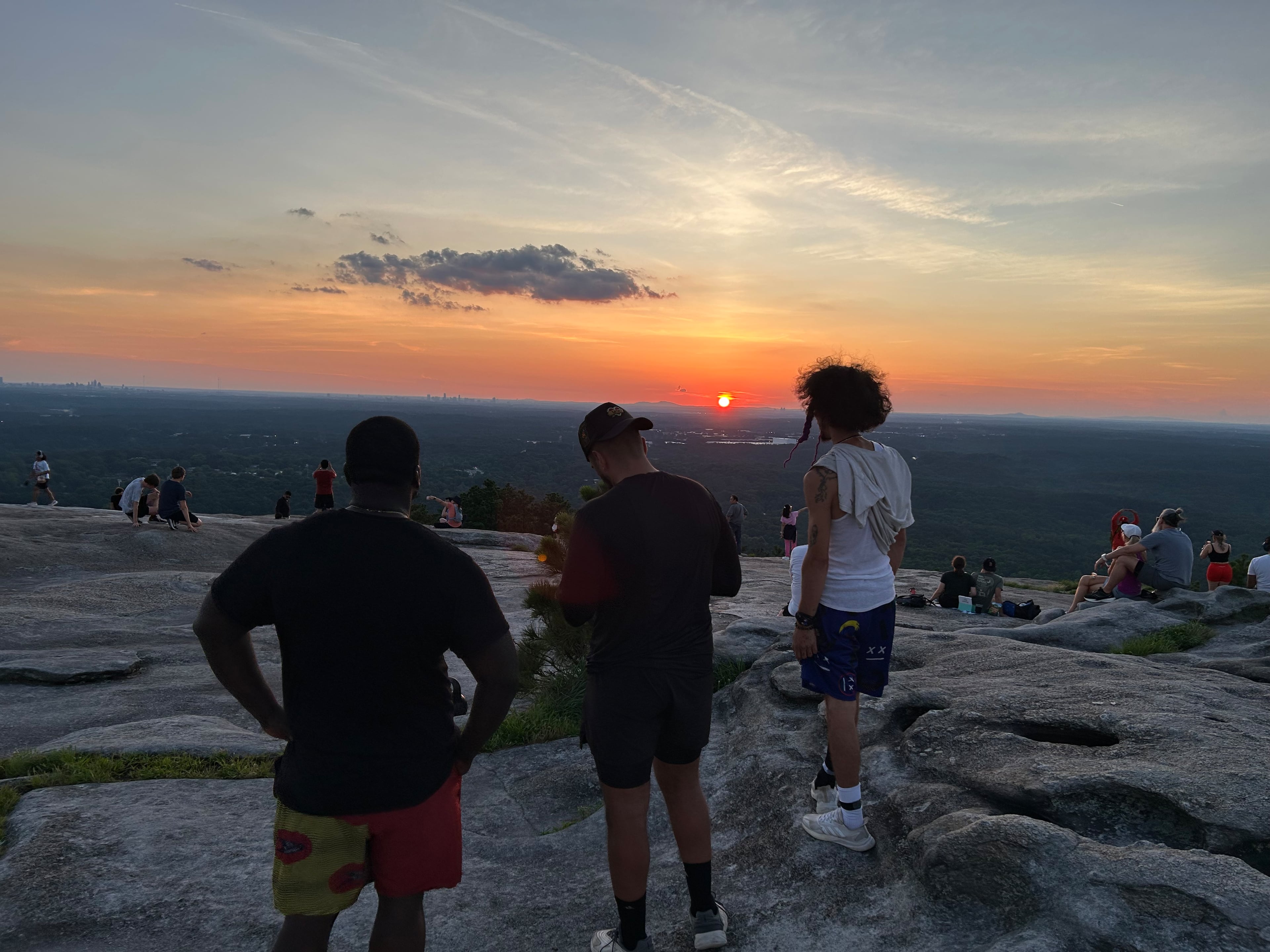 Friends Kelechi Emeonye (from left), Faris Mousa and Isaiah Ramirez stand on Stone Mountain and watch the sun set on the longest day of the year. It was all so majestic. Someone started clapping, and then someone else joined in. (Thomas Lake/AJC)
