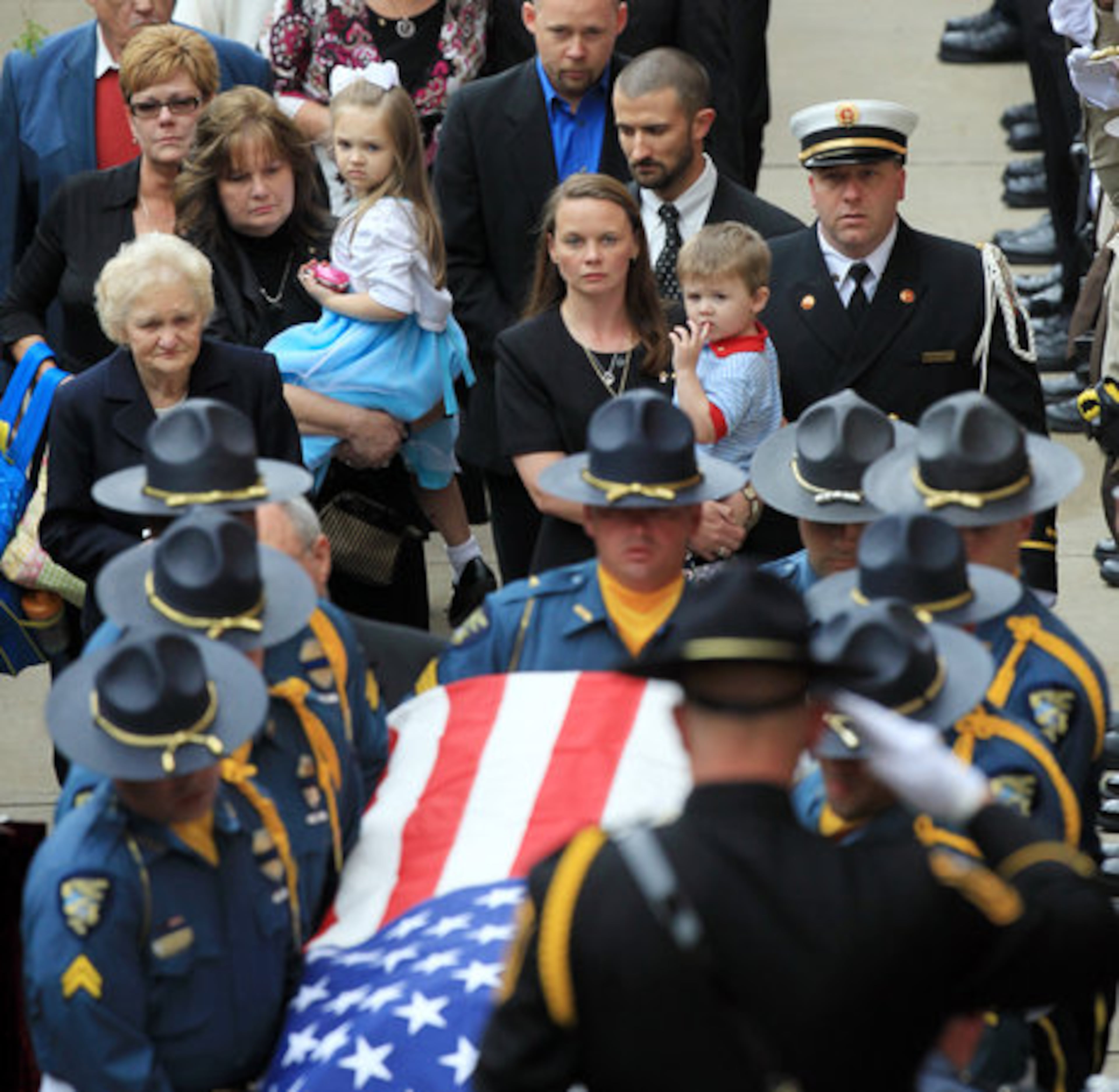 An officer salutes as the body of slain Athens Senior Officer Elmer "Buddy" Christian arrives for the funeral followed by his wife, children, and family members at the Classic Center Theatre in Athens on Sunday, March 27, 2011.