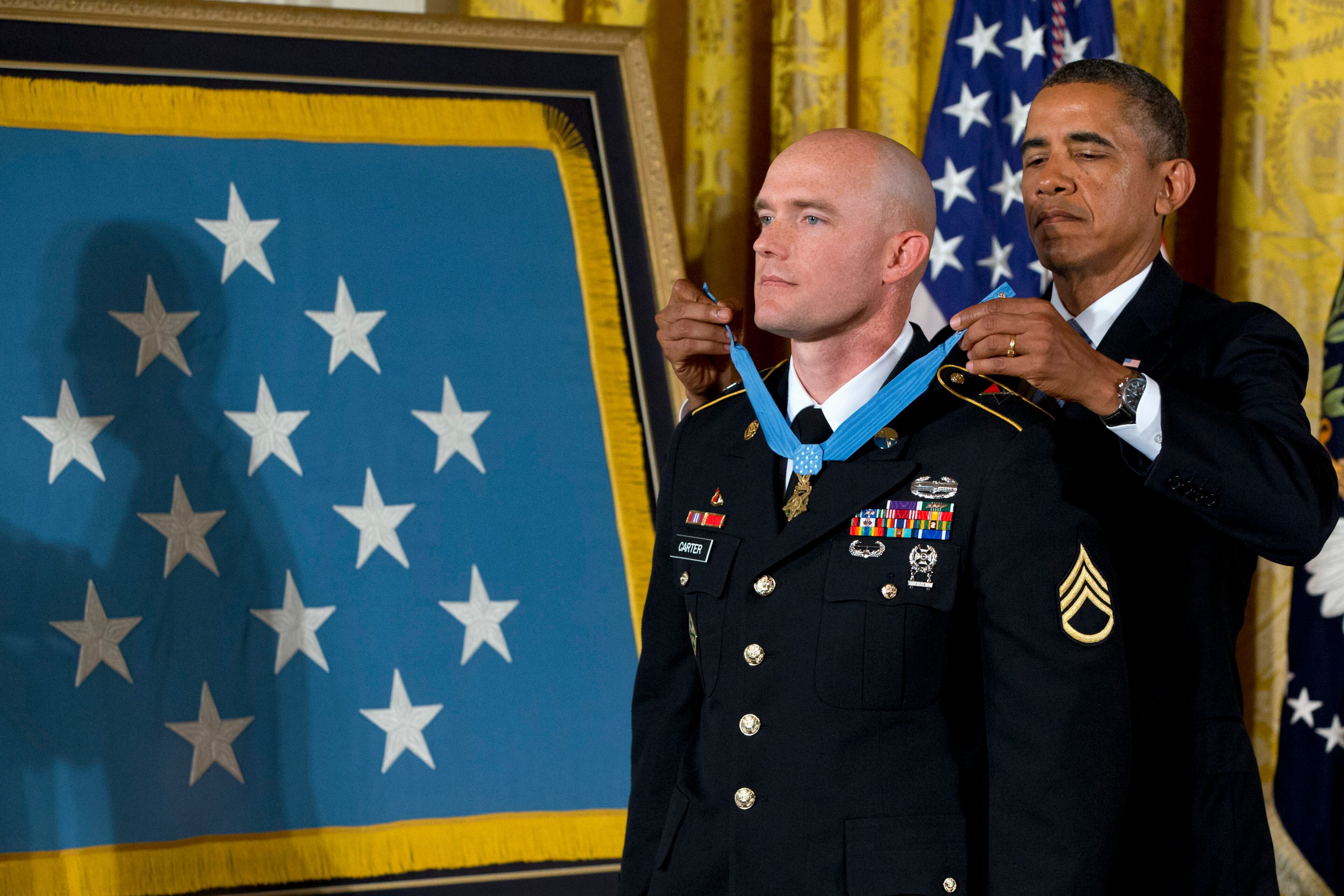 President Barack Obama awards US Army Staff Sgt. Ty M. Carter the Medal of Honor for conspicuous gallantry, Monday, Aug. 26, 2013, during a ceremony in the East Room of the White House in Washington. Carter received the medal for his courageous actions while serving as a cavalry scout with Bravo Troop, 3rd Squadron, 61st Cavalry Regiment, 4th Brigade Combat Team, 4th Infantry Division, during combat operations in Kamdesh District, Nuristan Province, Afghanistan on Oct. 3, 2009. Carter is the fifth living recipient to be awarded the Medal of Honor for actions in Iraq or Afghanistan. (AP Photo/Jacquelyn Martin)