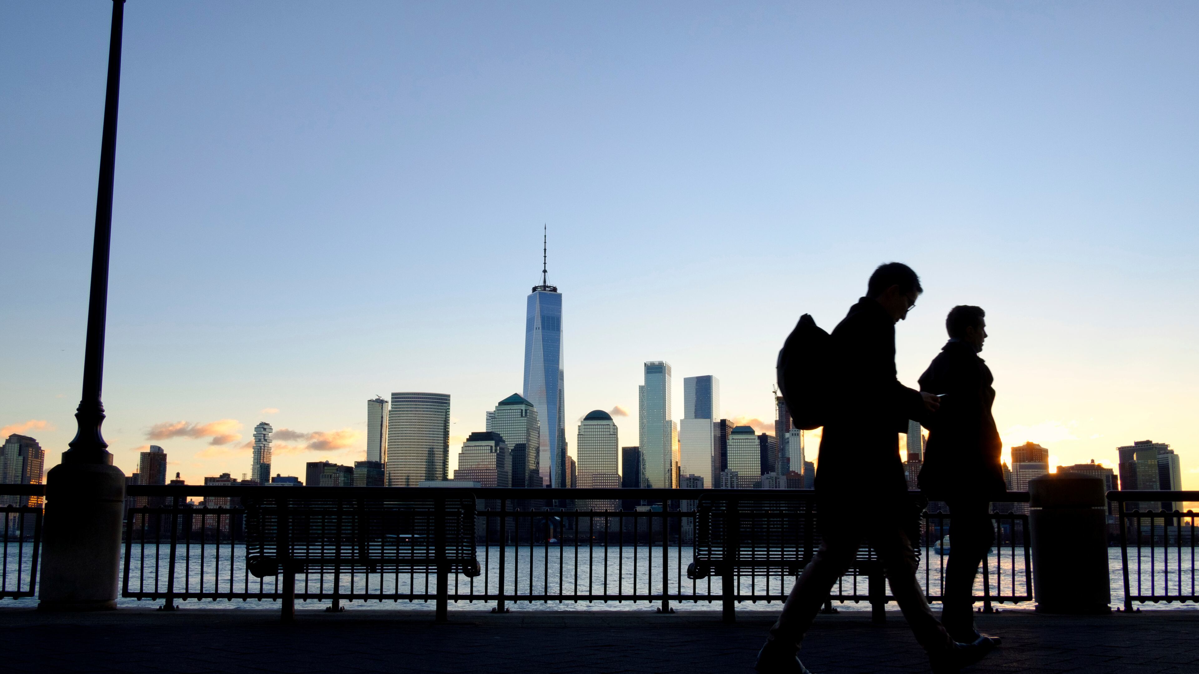 FILE - Early morning commuters on the New Jersey side of the Hudson River walk to work past the New York City skyline, Dec. 18, 2018, in Jersey City, N.J. (AP Photo/J. David Ake, File)