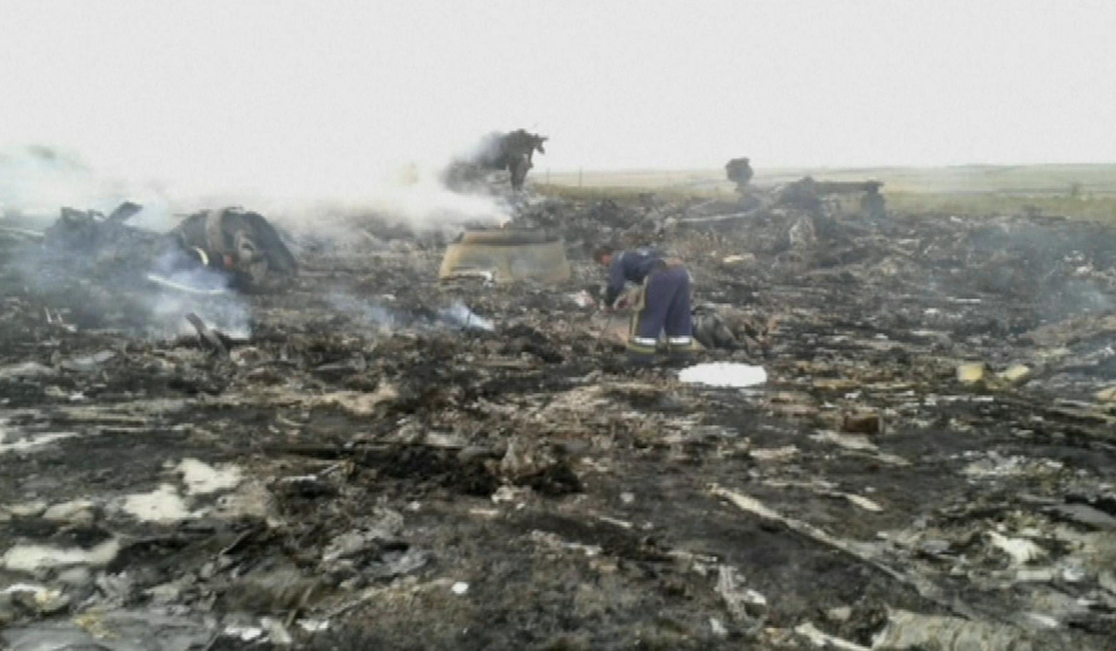 In this image taken from video, Thursday July 17, 2014, people walk amongst the debris at the crash site after a passenger plane carrying 295 people was shot down Thursday as it flew over Ukraine, near the village of Hrabove, in eastern Ukraine. Malaysia Airlines tweeted that it lost contact with one of its flights as it was traveling from Amsterdam to Kuala Lumpur over Ukrainian airspace. (AP Photo / Channel 1)