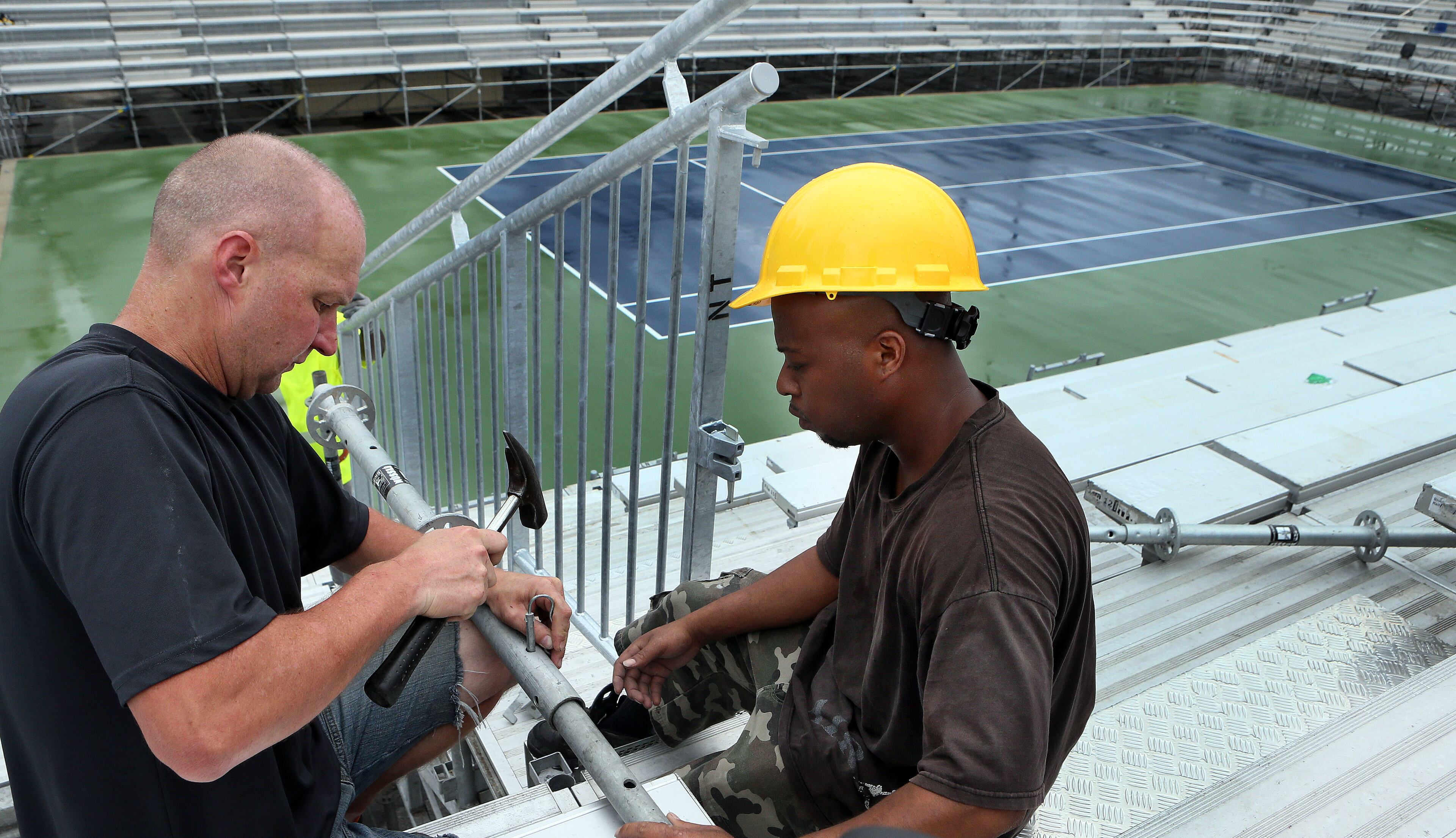 Andreas Pein (left) and Joedanta Collins install hand rails as crews construct the grand stands for the upcoming BB&T Atlanta Open men's pro tennis event at Atlantic Station.