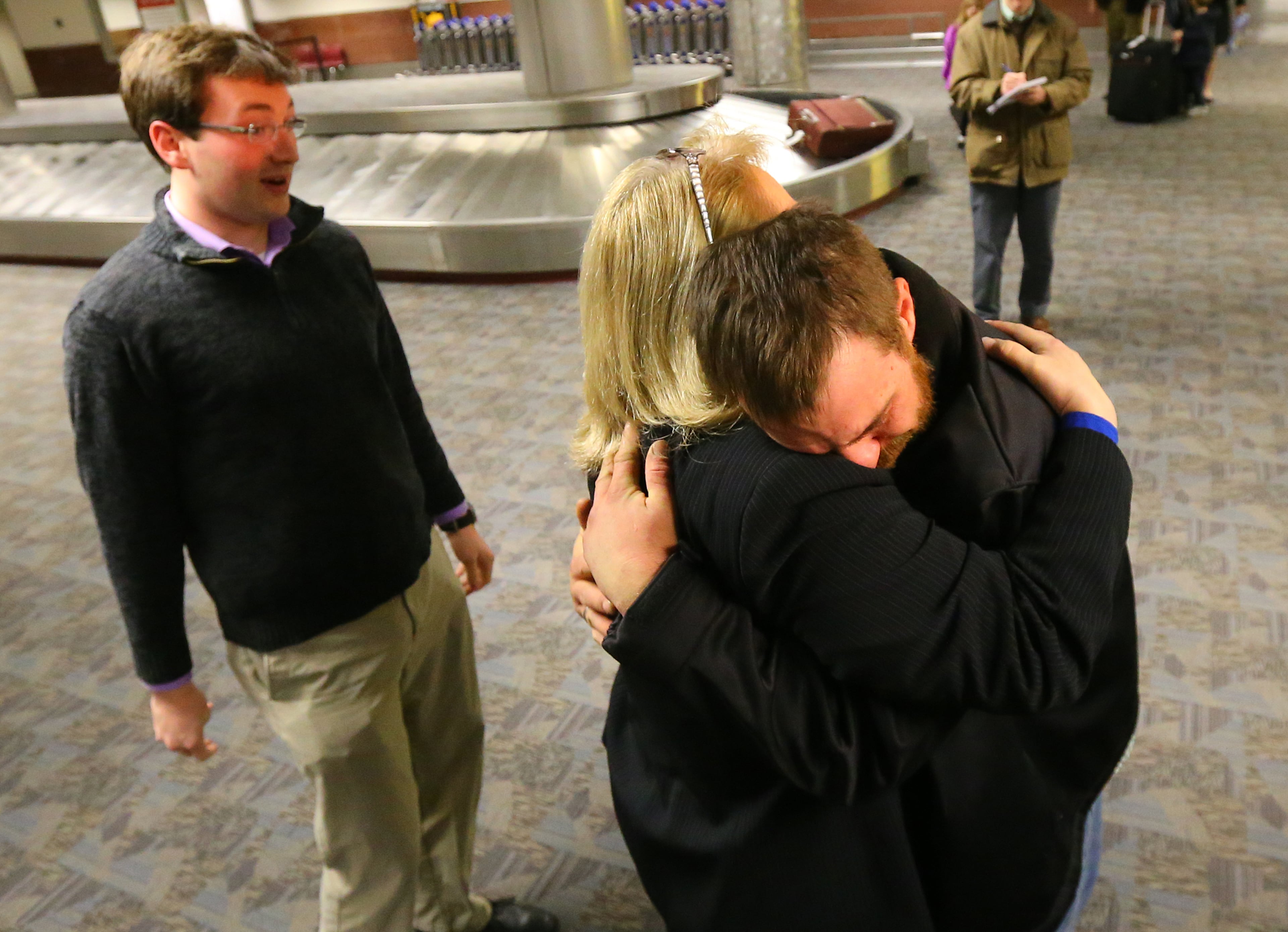 Joel Hartman, the homeless man who returned a woman's wallet he found while digging through trash hoping to find someone's leftover meal, is reunited with his family. Here, he hugs his stepmother, Deanna Rodecki, as his brother, Andrew Rodecki, looks on in baggage claim at Hartsfield-Jackson International Airport on Nov. 28, 2013, in Atlanta.