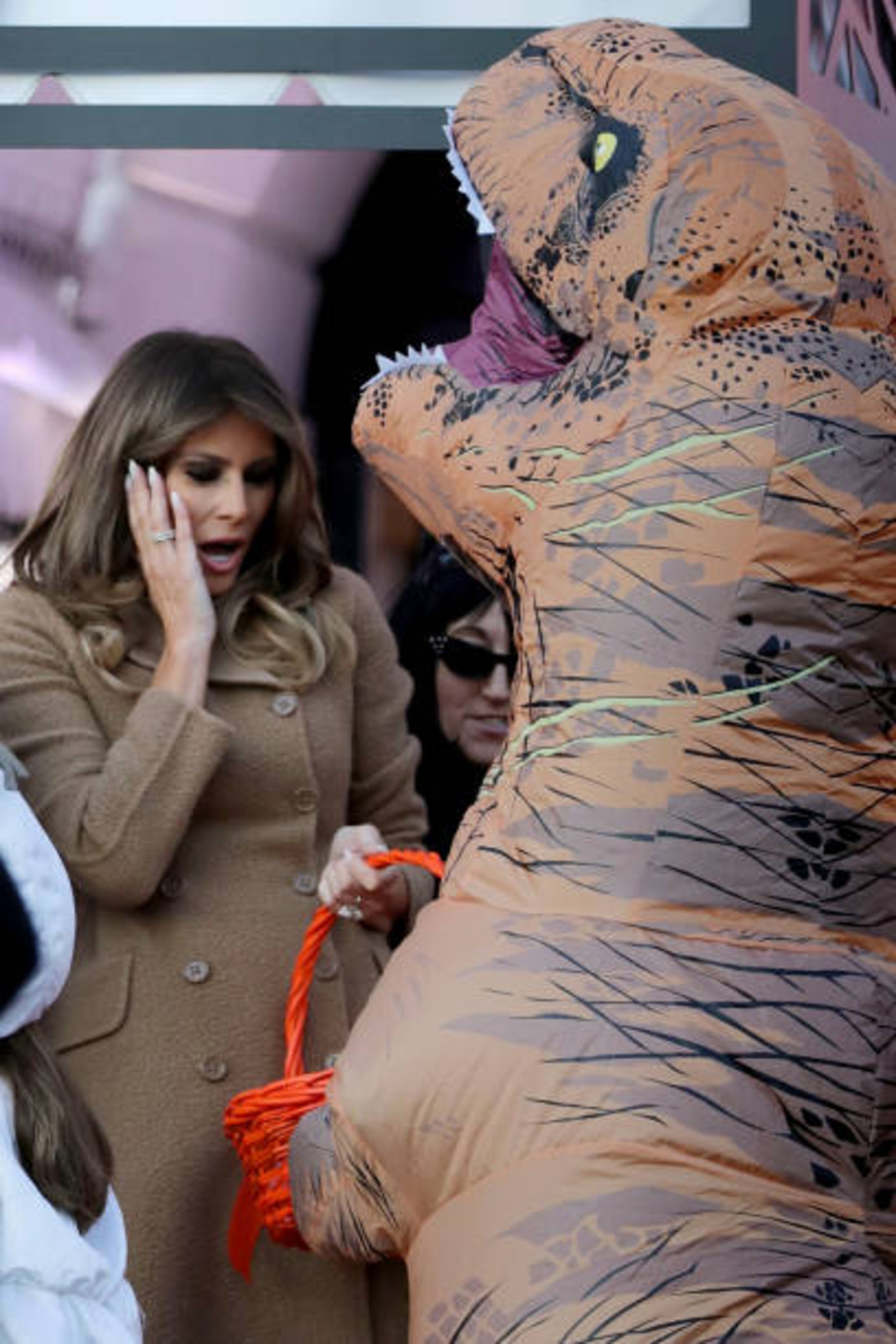 WASHINGTON, DC - OCTOBER 30: U.S. first lady Melania Trump reacts to the dinosaur costume worn by a trick-or-treater while hosting Halloween at the White House on the South Lawn October 30, 2017 in Washington, DC. The first couple gave cookies away to costumed trick-or-treaters one day before the Halloween holiday. (Photo by Chip Somodevilla/Getty Images)