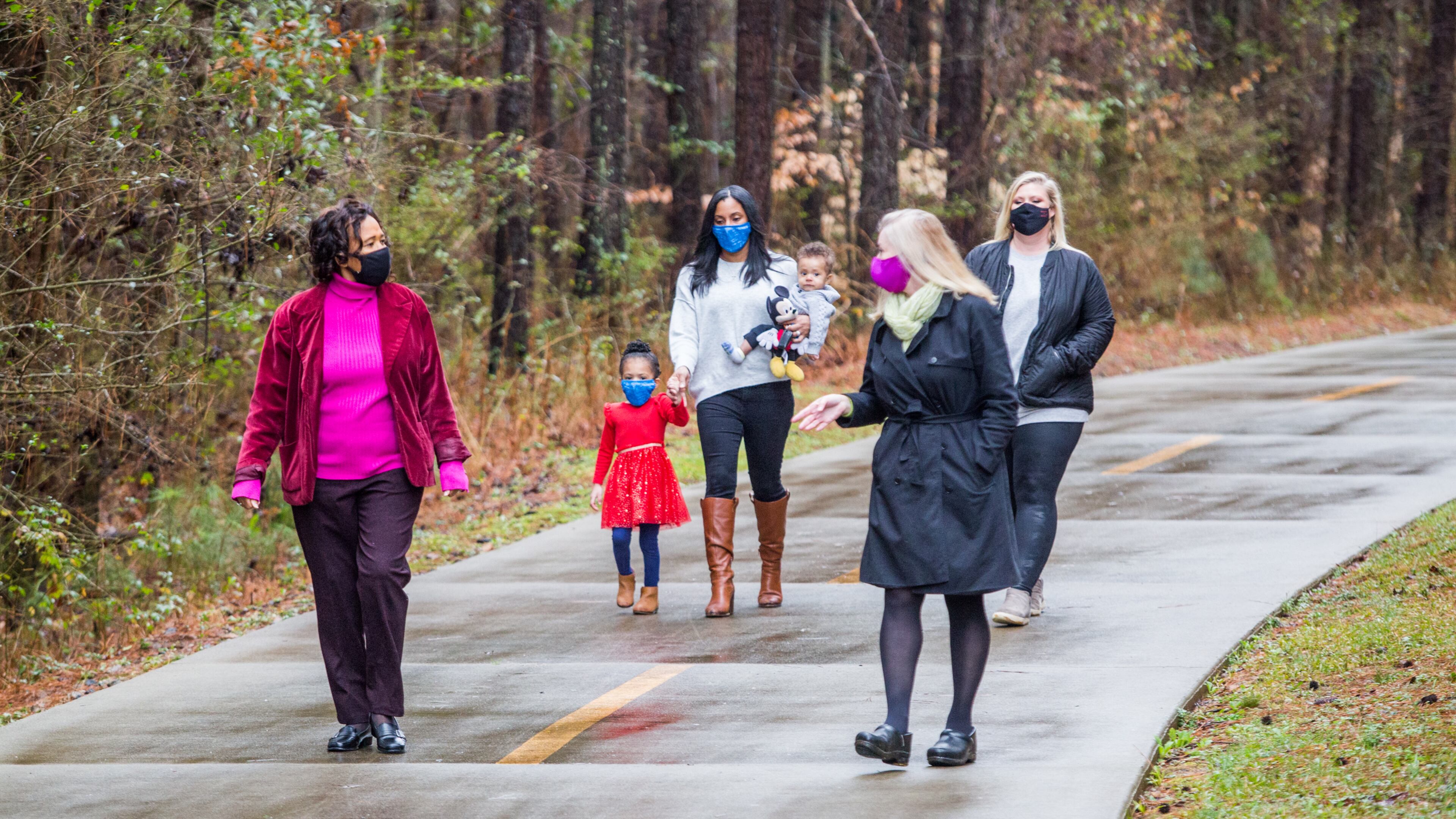 Blackwell film studio has traded land with DeKalb County making way for a new park with a splash pad, security, playgrounds and outdoor space for the Bouldercrest community. Neighborhood leaders, including Pat Culp, from left, the Clark family (Demi, 3; mother Alison, 7-month-old Lucas), Ingrid Buxbaum and Sarah Cotten, walk a path that will soon be part of the film studio Friday, Feb 12, 2021. A mile away, ground has been broken for the new DeKalb park. (Jenni Girtman for The Atlanta Journal-Constitution)