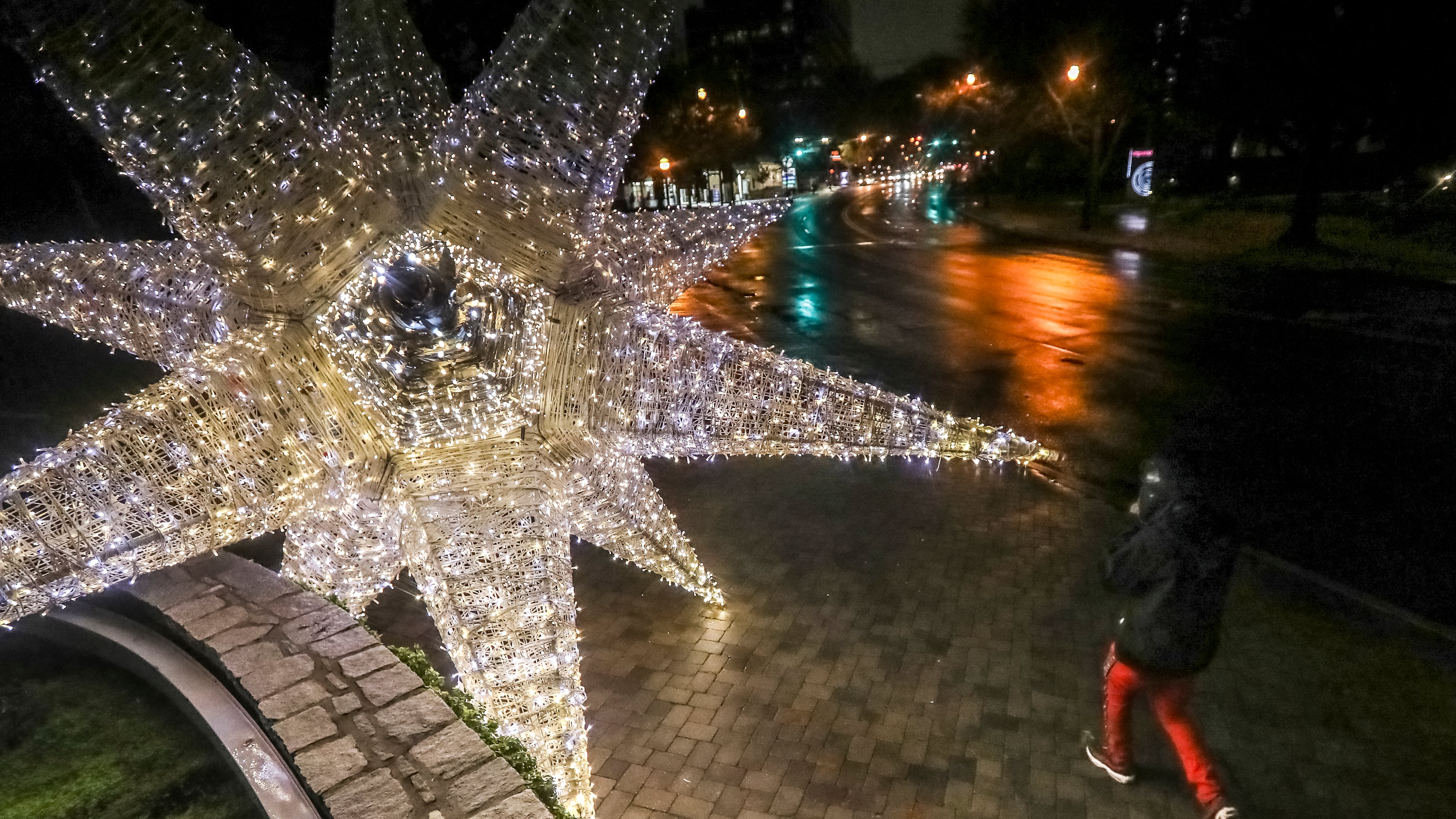 December 10, 2021 Atlanta: Gerald Stewart walks by a large illuminated holiday display at Peachtree Street and Beverly Road in Midtown Atlanta.