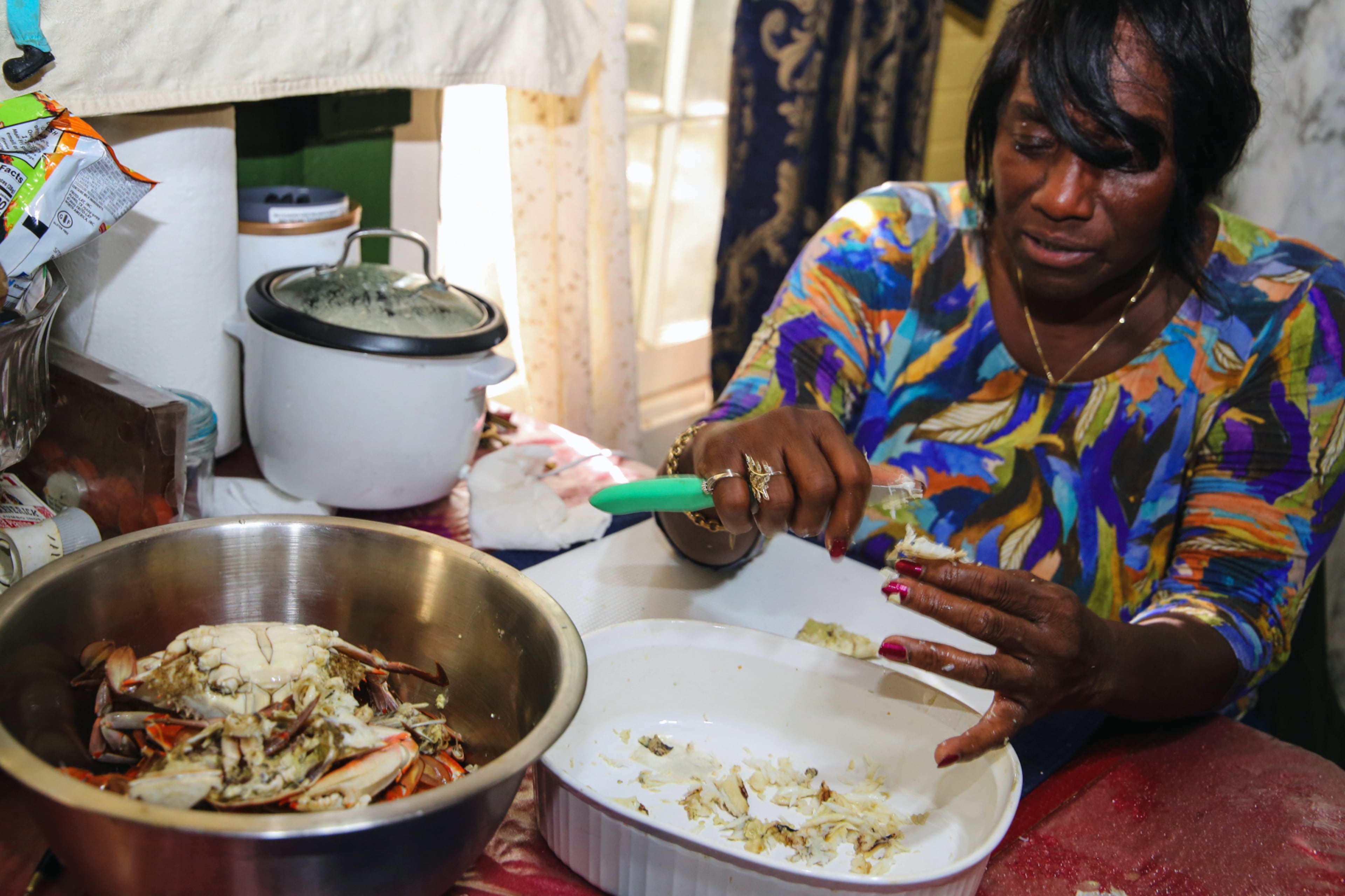 With practiced hands, chef and author Sallie Ann Robinson swiftly picks the sweet, tender crab meat from the legs and shells, showcasing her expertise and the efficiency honed by generations of island cooking in a photo from 2024. (Adriana Iris Boatwright for The Atlanta Journal-Constitution)