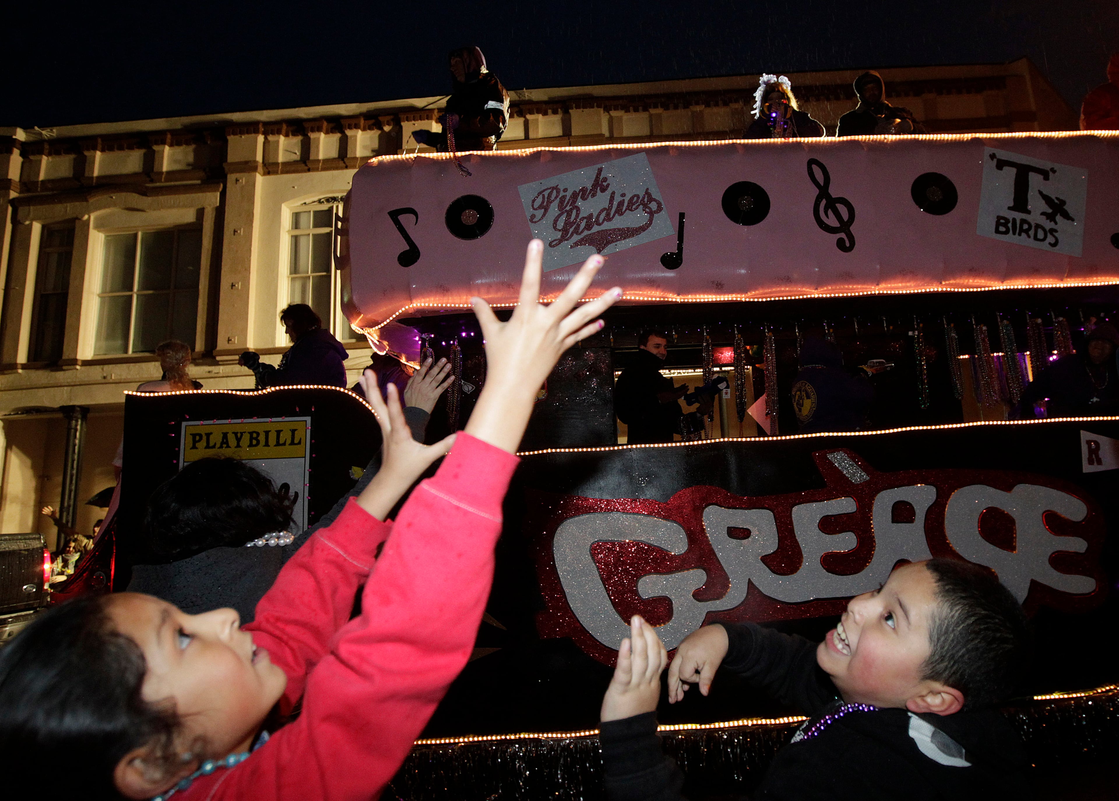 Anais Andalvz, 8, and Naason Maldonado, 9, grab for beads during the Mystic Krewe of Aquarius Fat Tuesday Parade to conclude Mardi Gras Galveston on Tuesday night March 4, 2014. (AP Photo/The Galveston County Daily News, Kevin M. Cox)