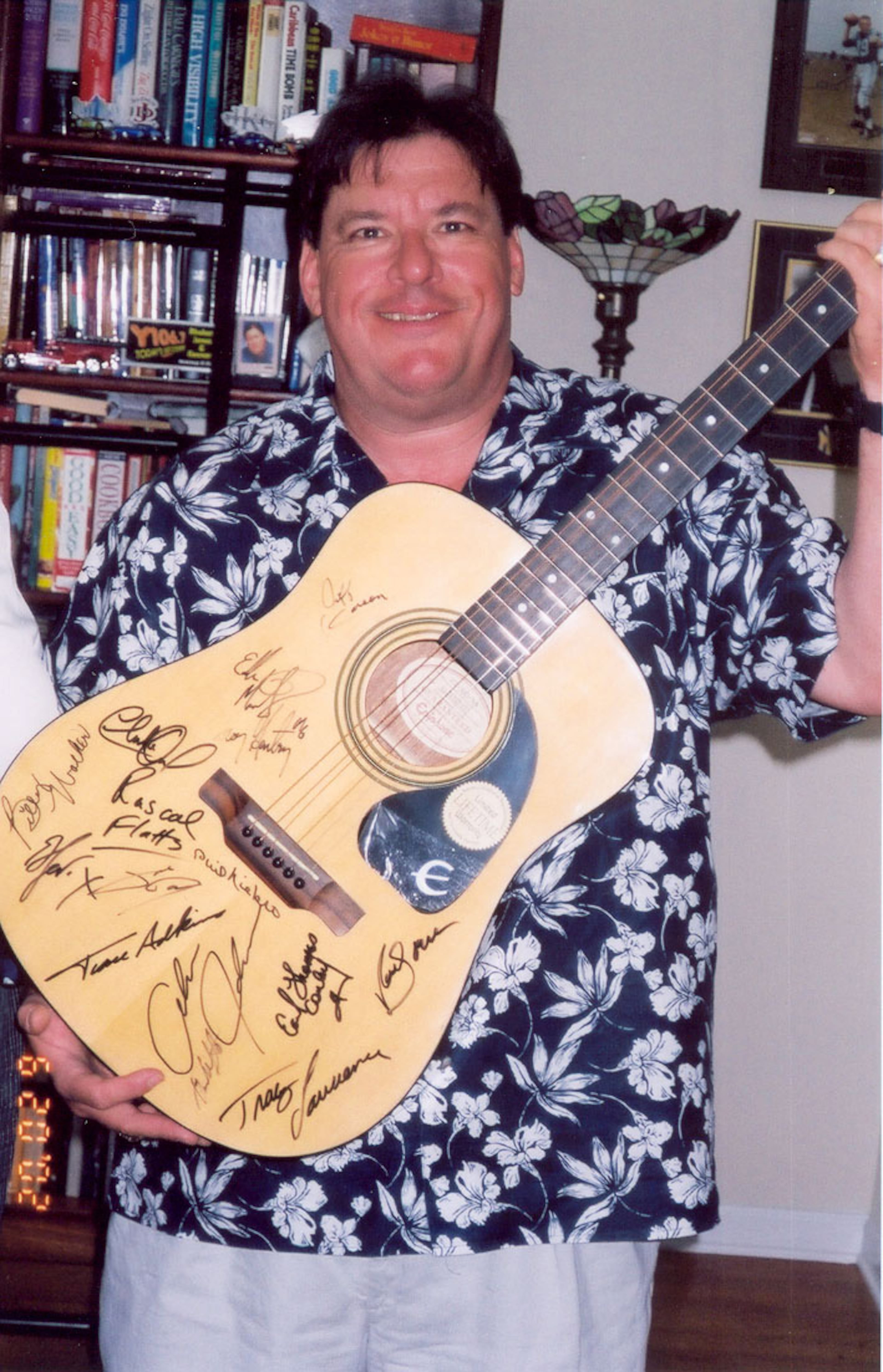 Disc jockey Rhubarb Jones shows off the autographed guitar to be auctioned off by Cobb Christmas Inc.