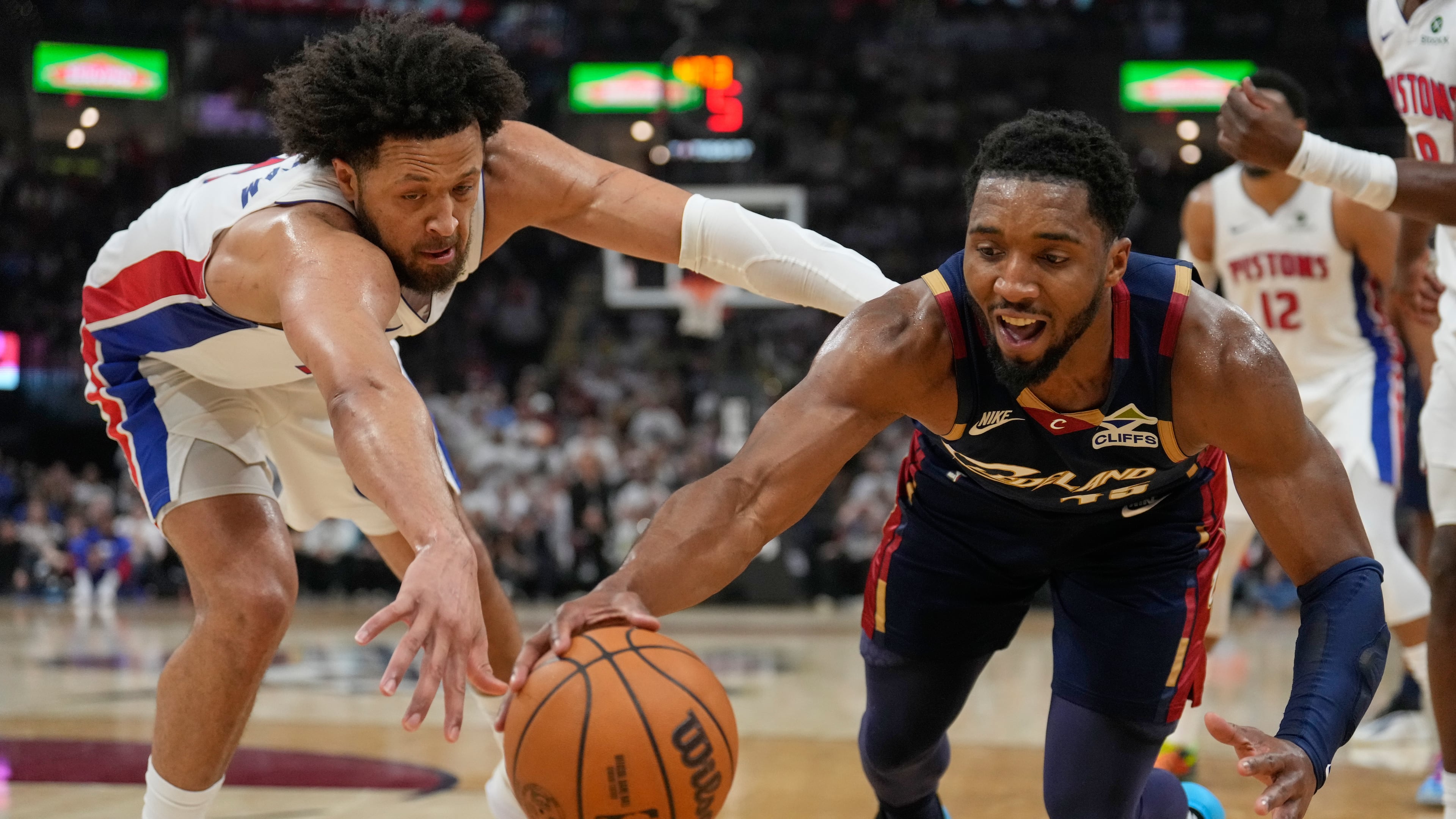 Detroit Pistons' Cade Cunningham, left, and Cleveland Cavaliers' Donovan Mitchell, right, reach for the ball in the first half of Game 4 of a second-round NBA basketball playoff series Monday, May 11, 2026, in Cleveland. (AP Photo/Sue Ogrocki)