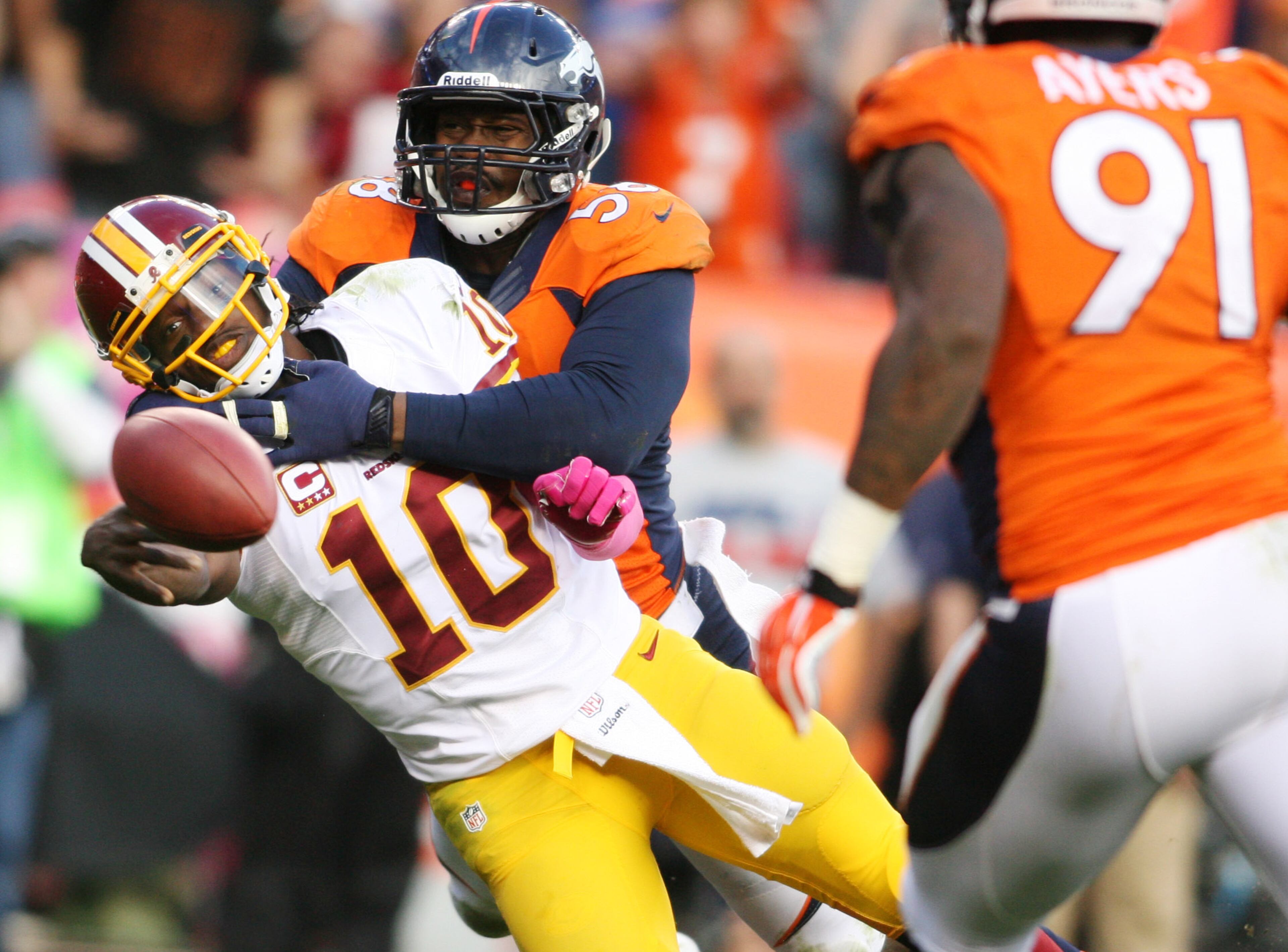 Washington Redskins quarterback Robert Griffin III (10) throws the ball away as he's hit by Denver Broncos linebacker Von Miller (58) during the second half at Sports Authority Field at Mile High. The Denver Broncos beat the Washington Redskins 45-21. Mandatory Credit: Chris Humphreys-USA TODAY Sports
