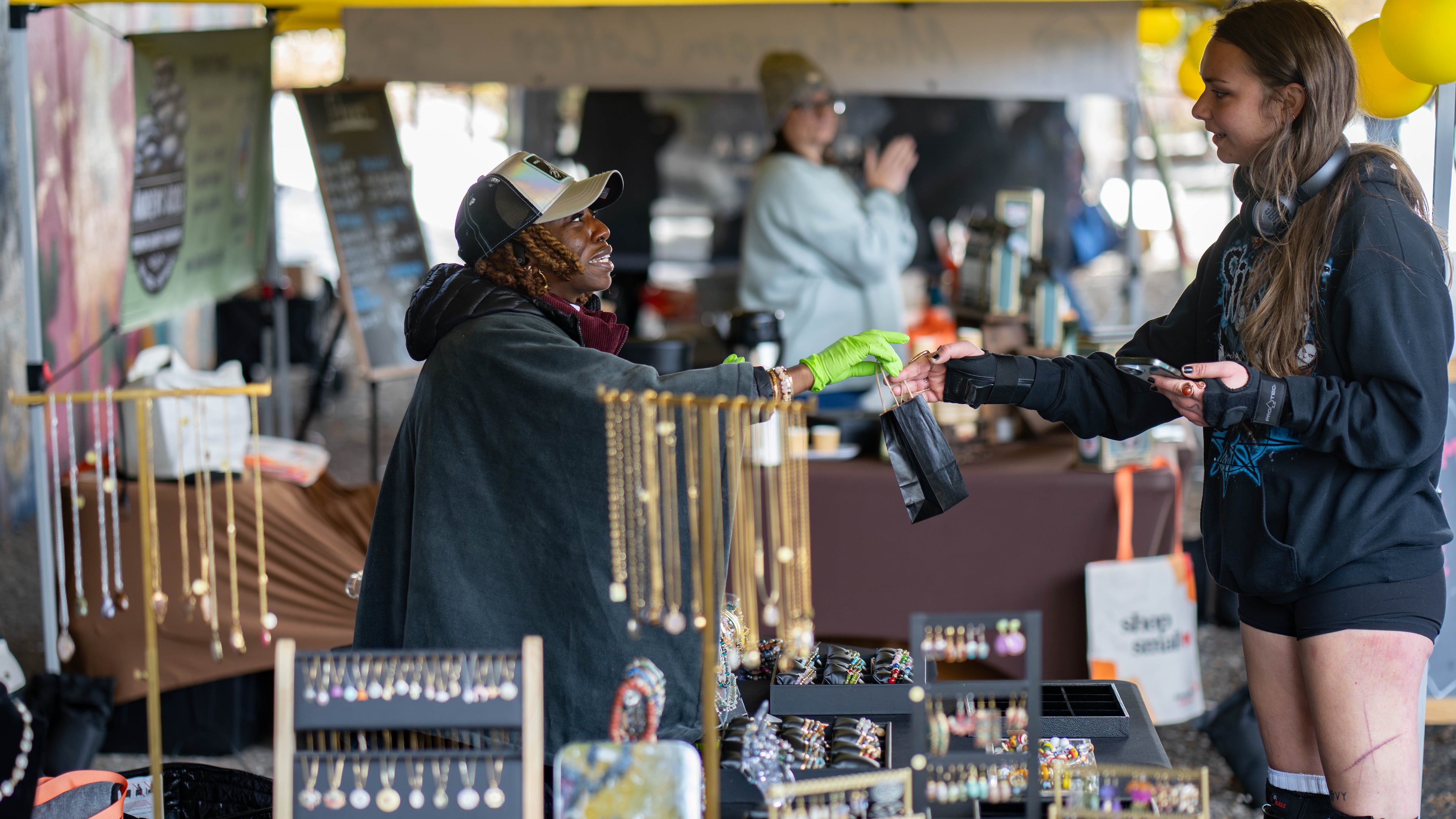 Christina Mondestin (left) owner of Beni Destiné jewelry, sells a necklace at her booth at the Atlanta Beltline Marketplace's annual Small Business Saturday event on Nov. 29, 2025. (Ben Hendren for the AJC)