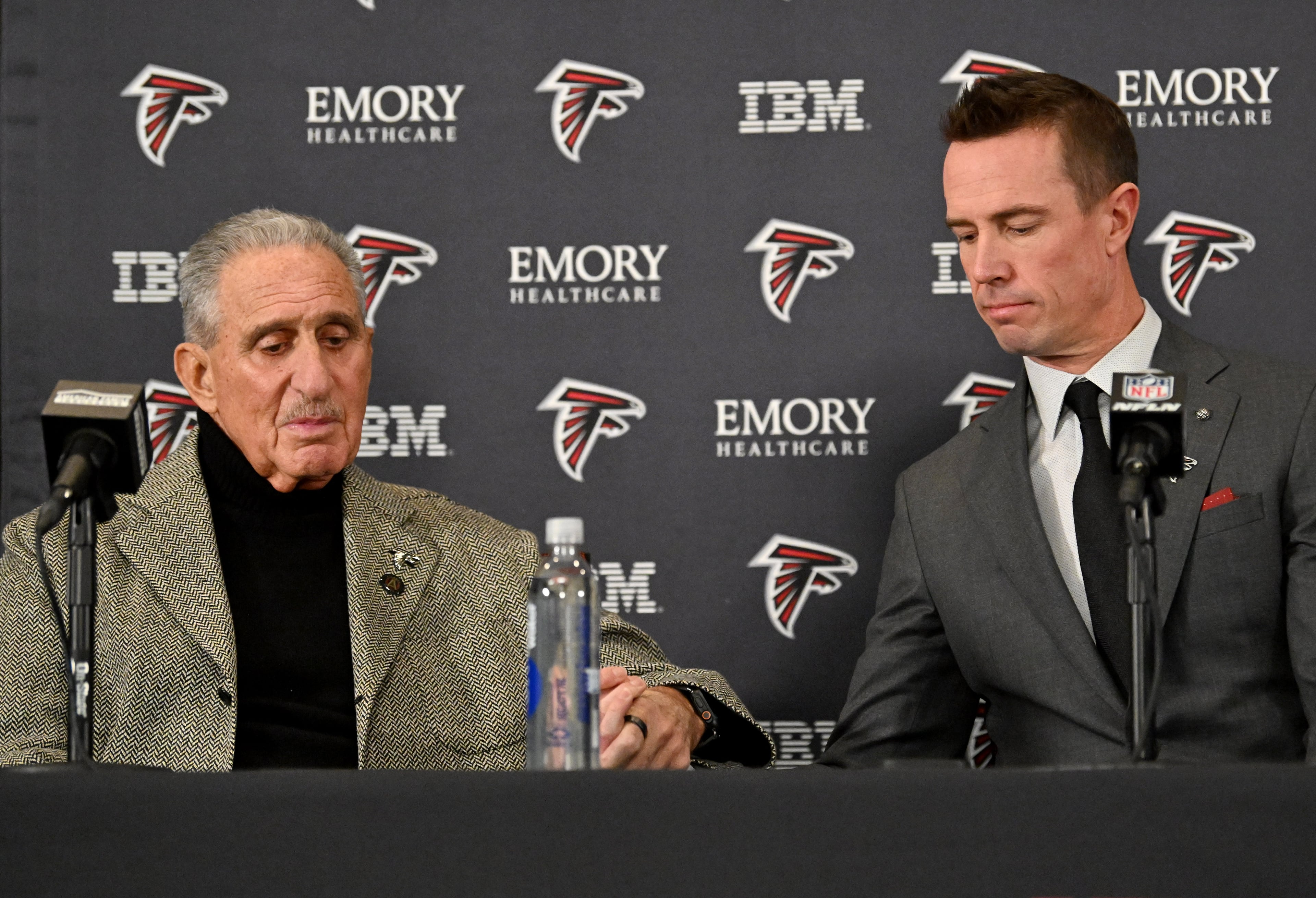 Atlanta Falcons owner Arthur Blank holds a hand of new Atlanta Falcons president of football Matt Ryan as he speaks to members of the press during a news conference to introduce new Falcons president of football Matt Ryan, Tuesday, Jan. 13, 2026, in Flowery Branch. (Hyosub Shin/AJC)