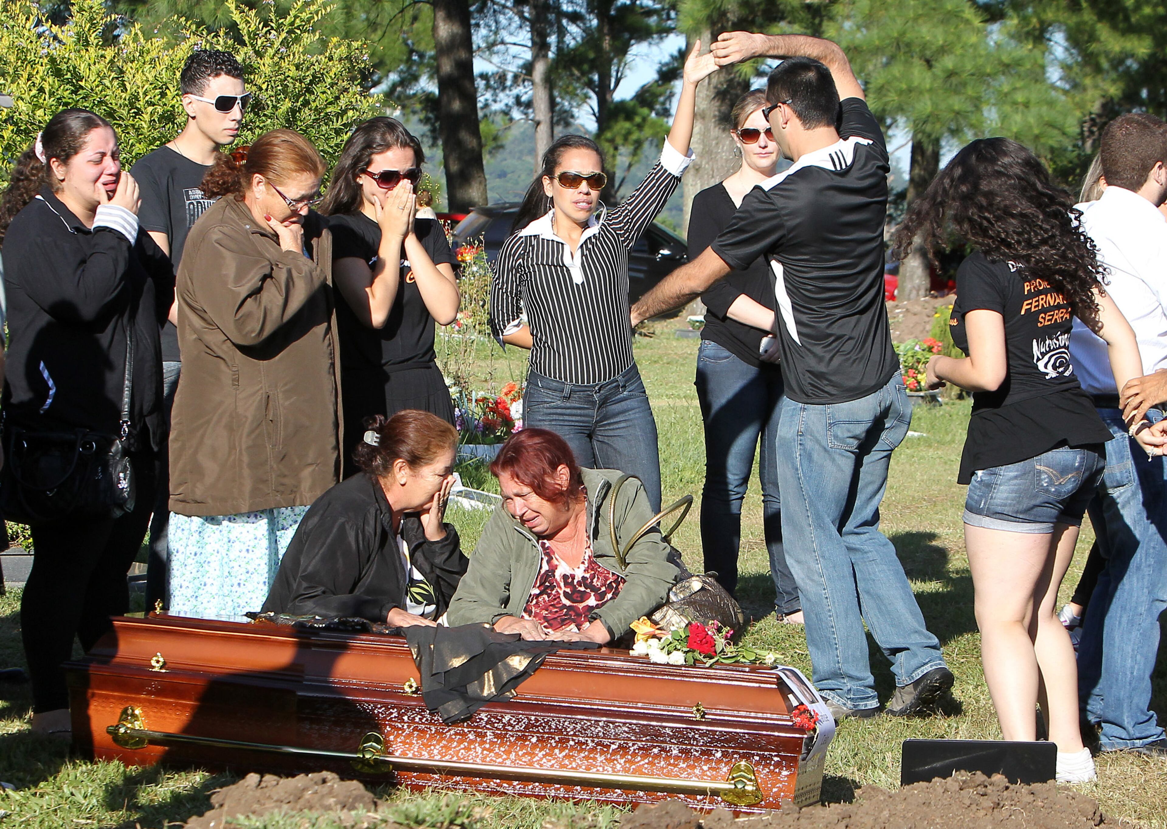 Relatives and friends dance and mourn next to the coffin during the burial of fire victim Tanise Cielo, at a cemetery in Santa Maria city, Rio Grande do Sul state, Brazil, Monday, Jan. 28. The city in southern Brazil started burying the 200 people killed in Sunday's fire at the Kiss nightclub after the conflagration caused by a band's pyrotechnic display.