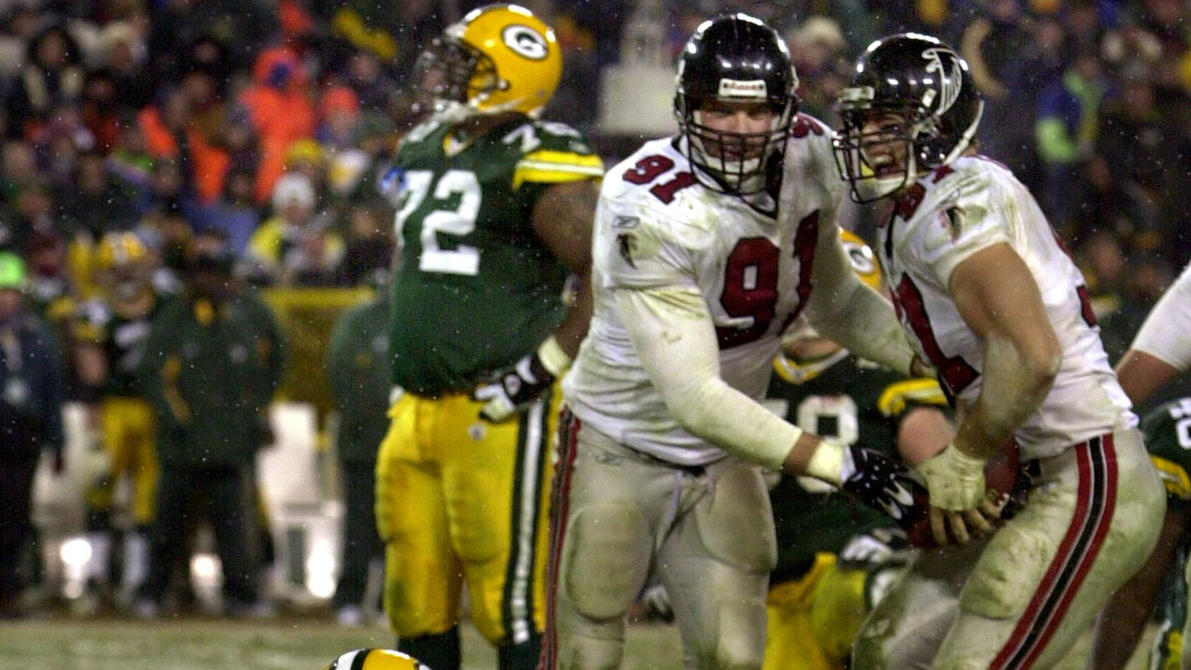 Packers quarterback Brett Favre sits dejected in the snow as Falcons defensive ends Brady Smith (center) and Patrick Kerney come up with his fumble celebrating during 4th quarter. (Curtis Compton/AJC)