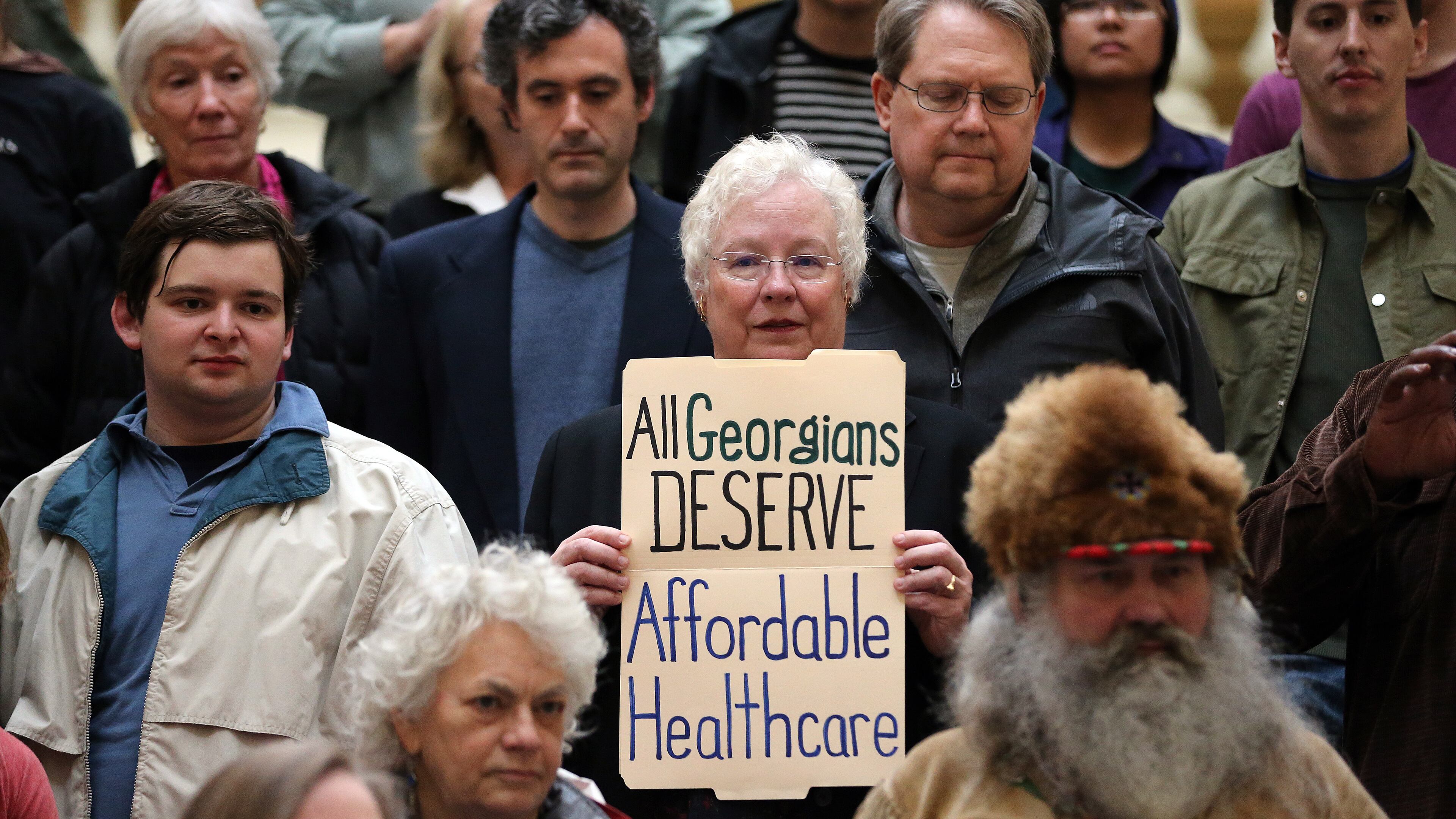 Steve Toggerson, center, holds a sign in favor of the expansion of Medicaid during a Moral Monday rally March 2, 2015 at the State Capitol. Twelve people were later arrested when they refused to leave a stairway at the State Capitol following the rally. BEN GRAY / AJC FILE PHOTO