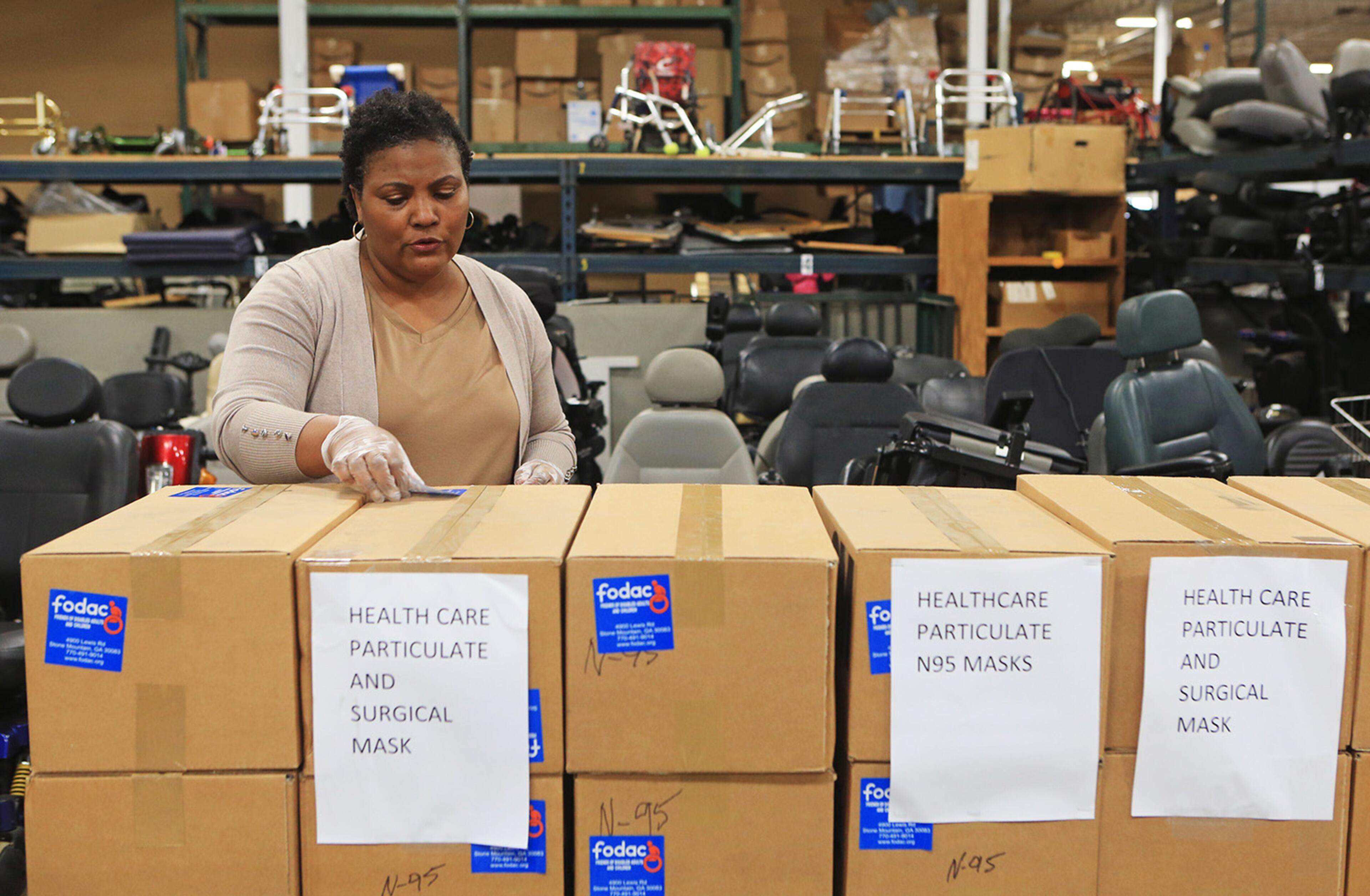 Sandra Guthrie, director of operations and administration at FODAC, puts stickers on boxes of masks and other medical supplies for delivery to Grady Hospital on Tuesday, March 24, 2020, at the FODAC warehouse in Tucker, Georgia. (Christina Matacotta, for The Atlanta Journal-Constitution)
