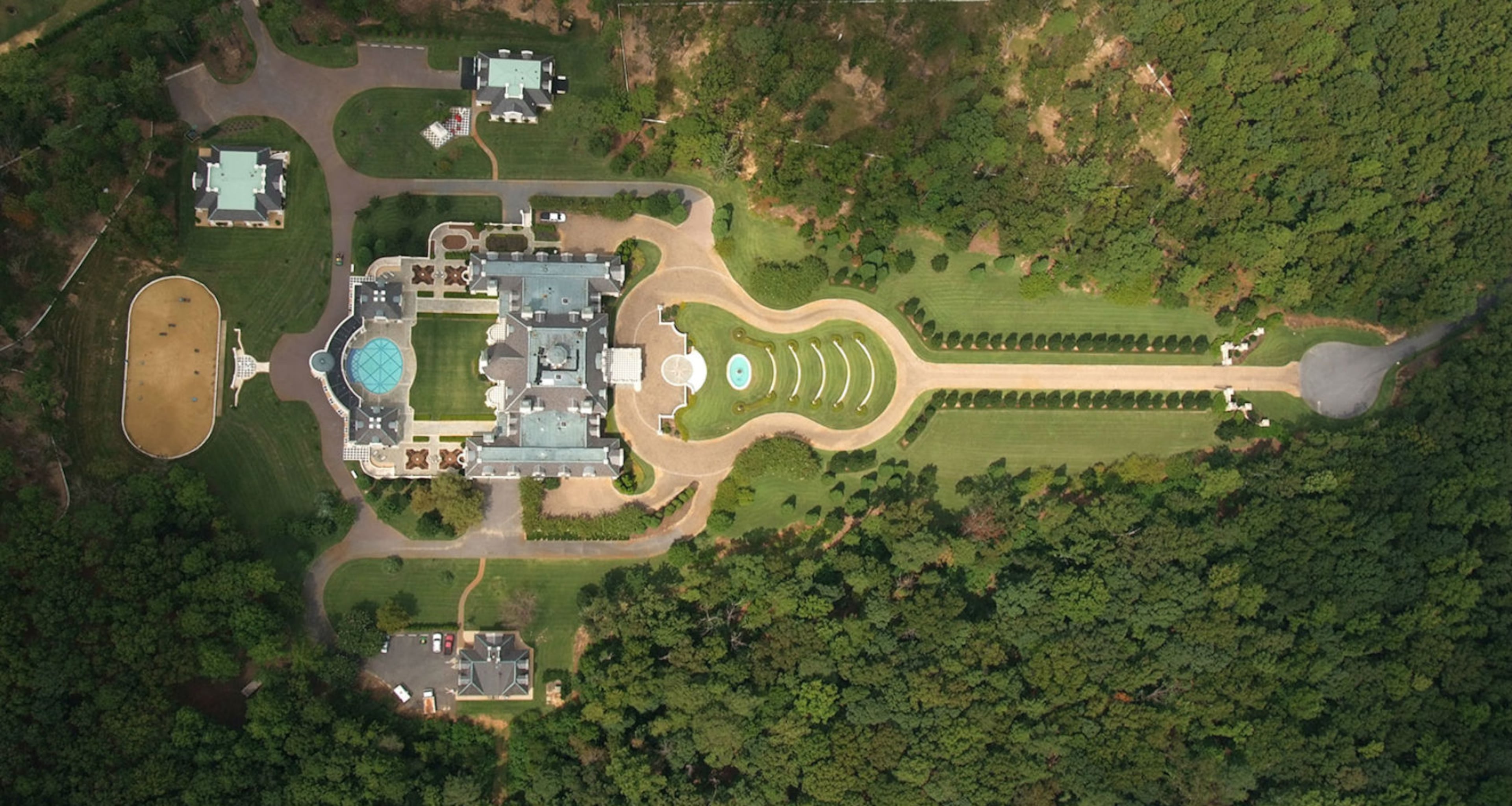The property’s stone driveway, designed in the shape of a guitar, is surrounded by landscaping and a fountain.