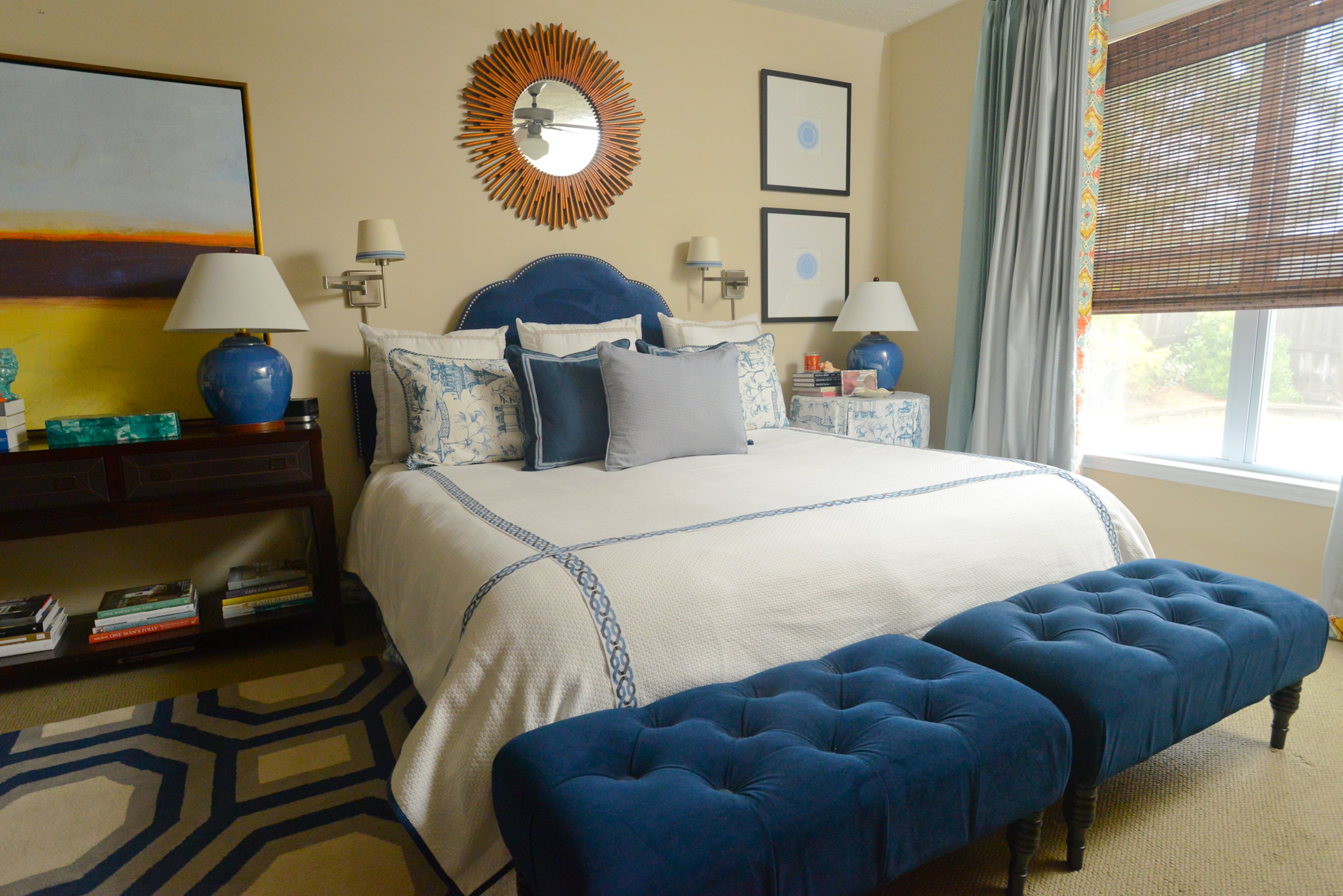 Designer Travis Snyder mixed patterns to make things more interesting in the part-traditional, part-contemporary master bedroom. A blue upholstered headboard from Wayfair and blue benches from Target tie together the patterned rug and textiles on the bed and pillows.