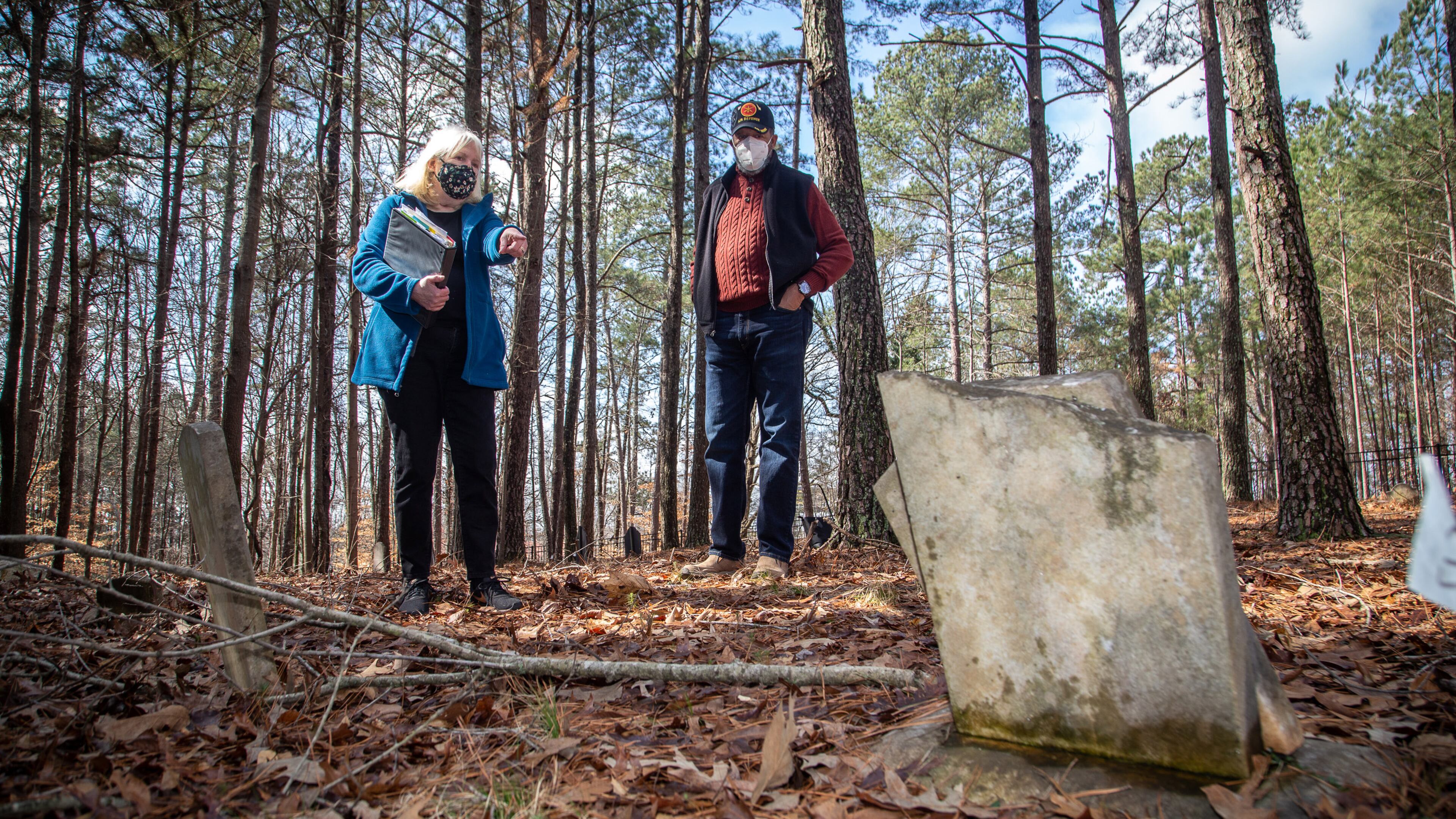 Johns Creek's Historical Society president Joan Compton (L) and Johns Creek's Historical Society Board Member Kirk Canaday look over a headstone at the Macedonia Cemetery in 2021. Johns Creek is might form a nonprofit that would provide guidance in the restoration and preservation of a cemetery where former enslaved people and their relatives are buried. STEVE SCHAEFER FOR THE ATLANTA JOURNAL-CONSTITUTION