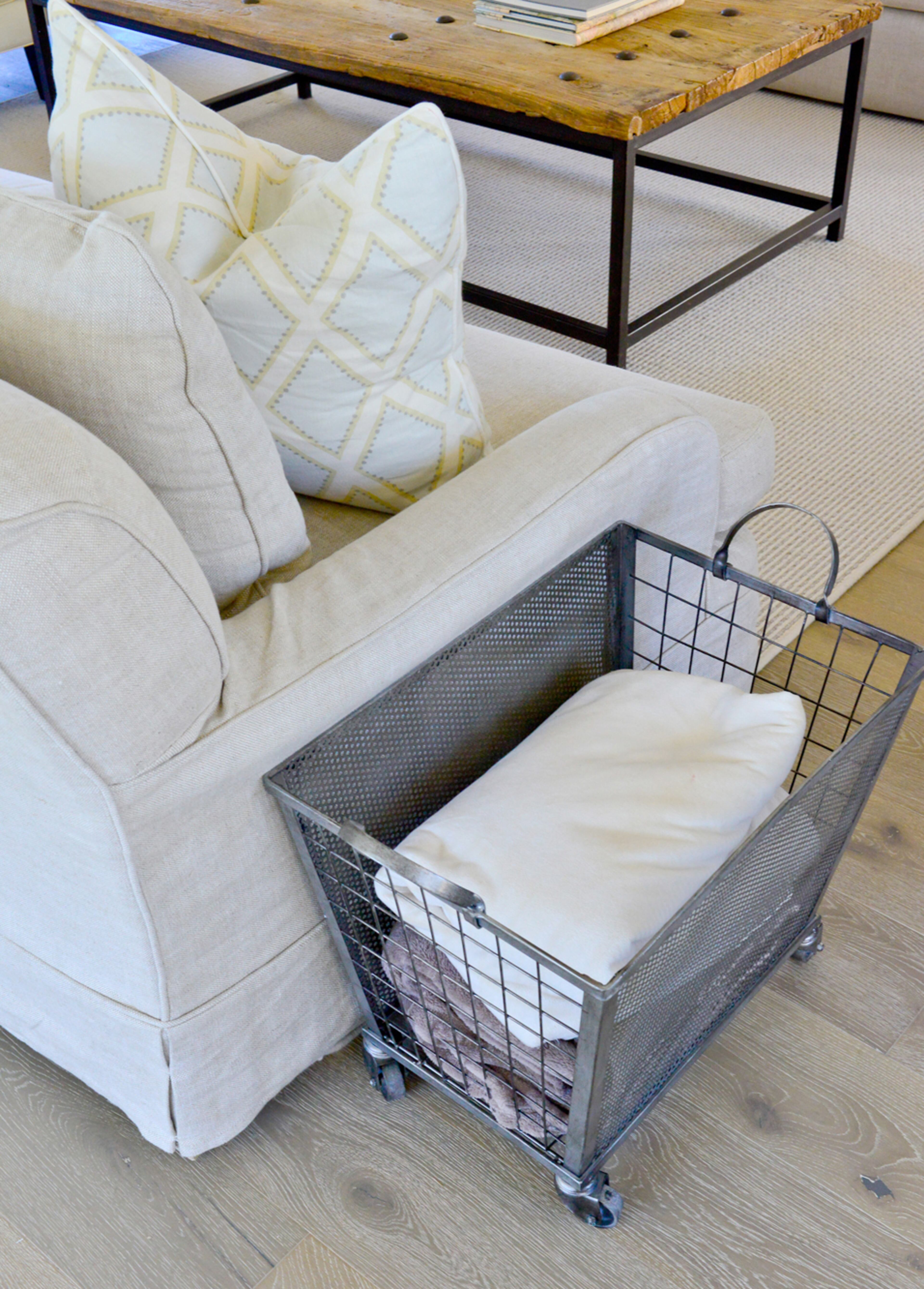 A wire basket on wheels offers portable storage for blankets, or items such as toys.