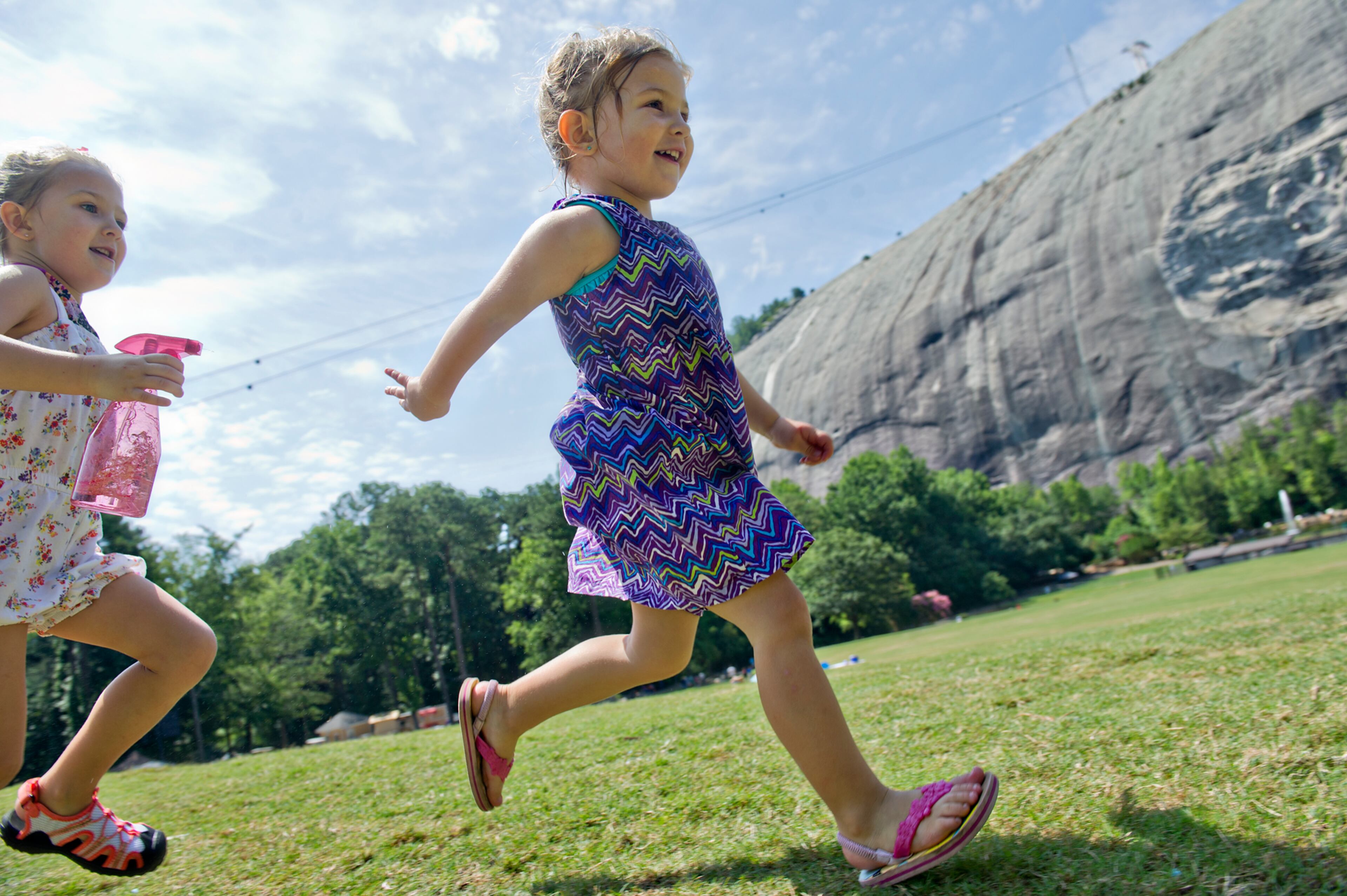 Gabraila Bartlett (left) chases after her sister Caroline with a water bottle on the main lawn at Stone Mountain Park during the Fantastic Fourth celebration weekend on Saturday, July 5, 2014.
