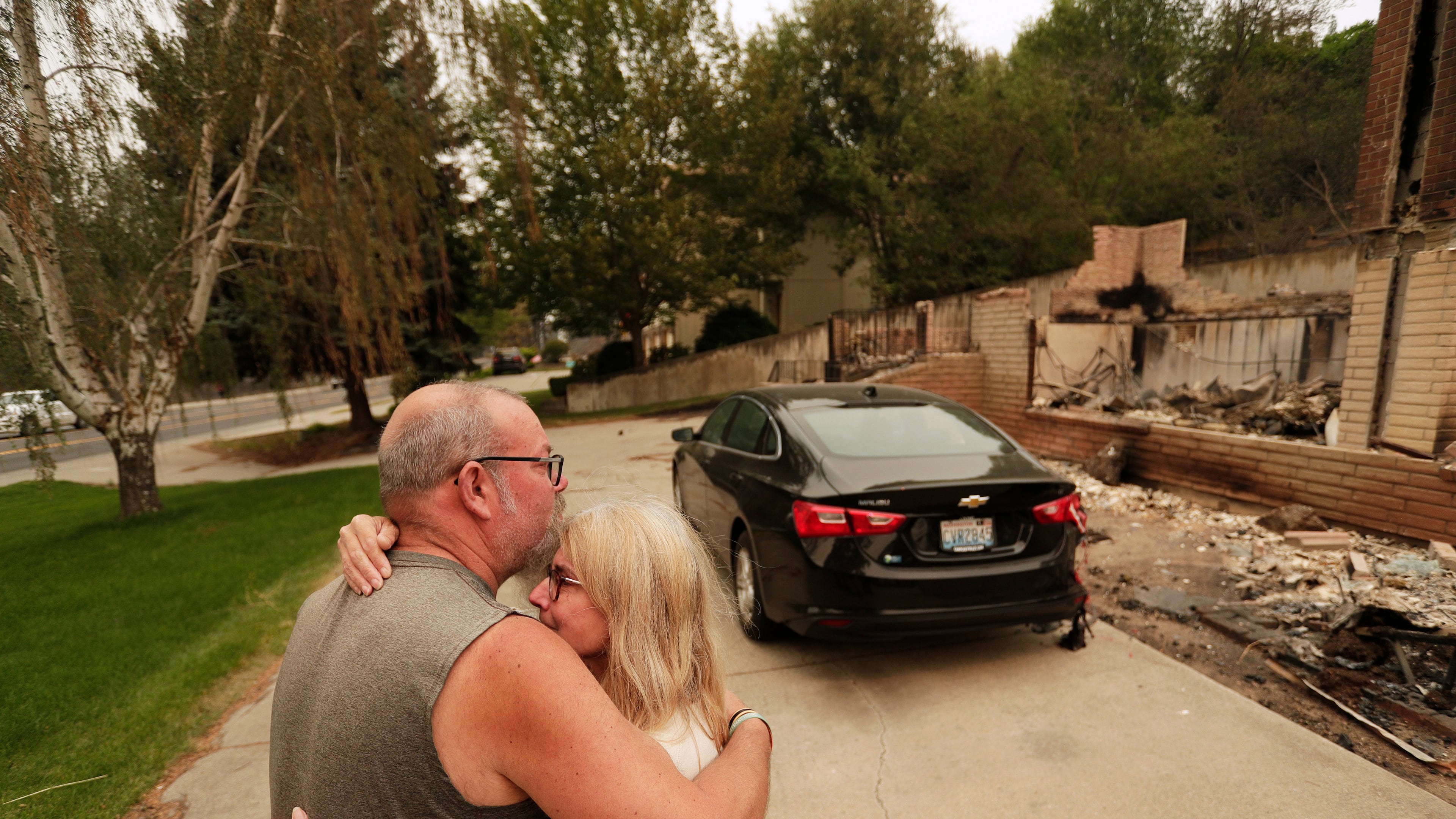 Allen Sather and his wife Kimberley embrace at the duplex they rent on W. Indian Trail Rd. after it burned in a wildfire in Spokane, Wash., Sunday, Aug. 2, 2026. (AP Photo/Young Kwak)